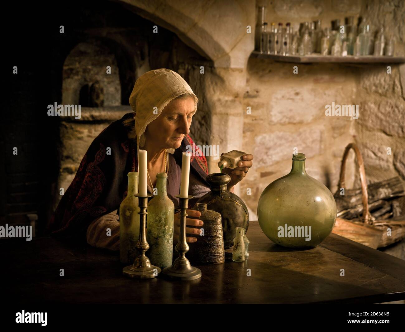 Femme en tenue médiévale travaillant comme un alchimiste ou une sorcière dans la cuisine d'un château médiéval français - avec des biens Banque D'Images