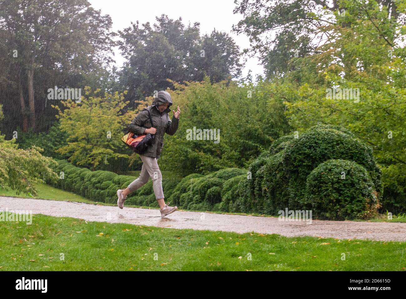 Femme en train de courir sous la pluie et de s'mouiller Banque D'Images