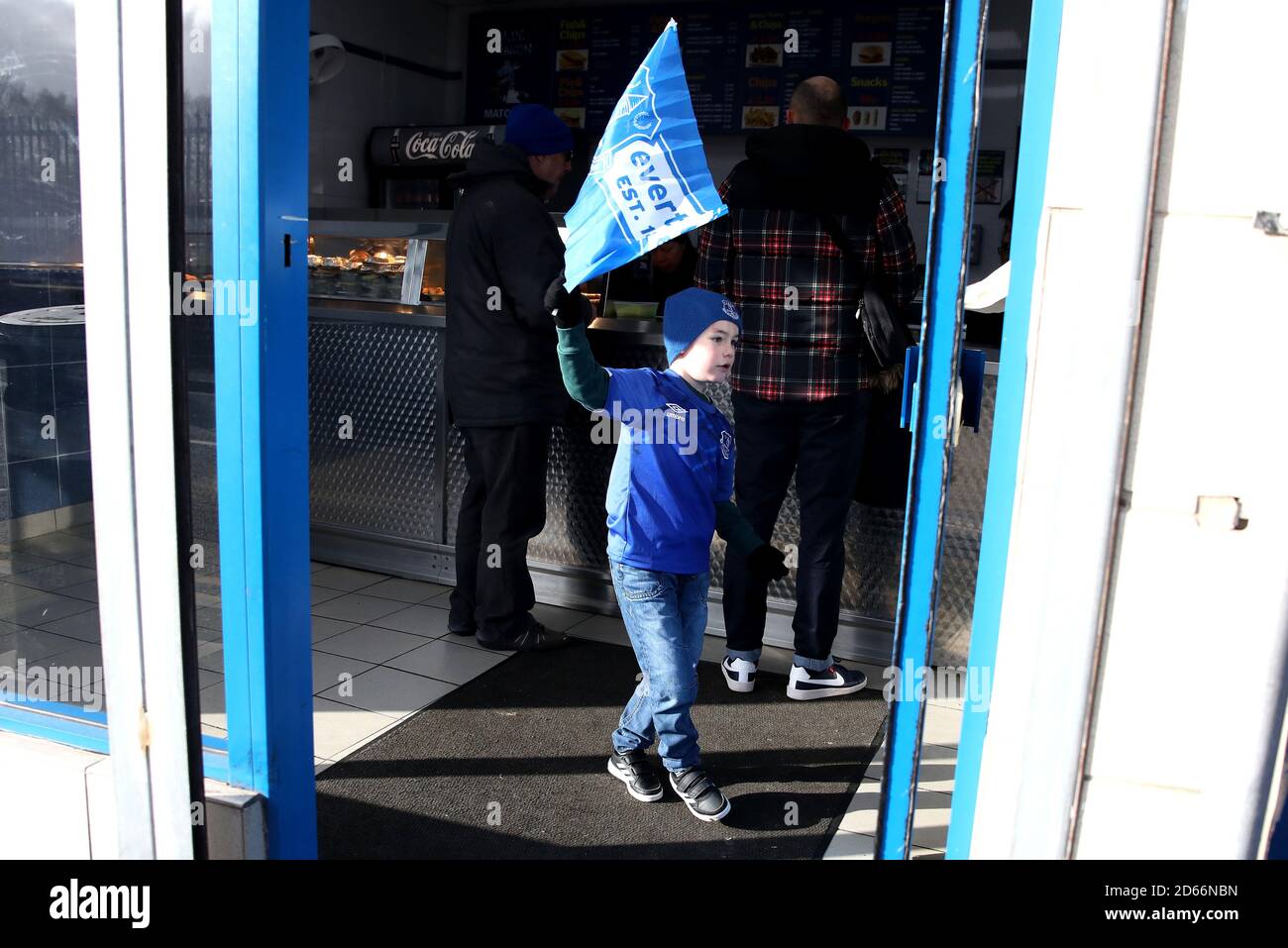 Un jeune fan d'Everton a son drapeau dans une boutique de poissons et de jetons Banque D'Images