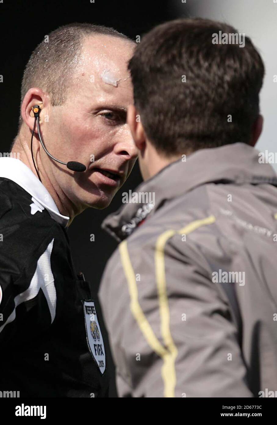 L'arbitre Mike Dean reçoit un traitement du personnel médical après avoir été frappé sur le front par un objet projeté du Stand Cardiff City Banque D'Images