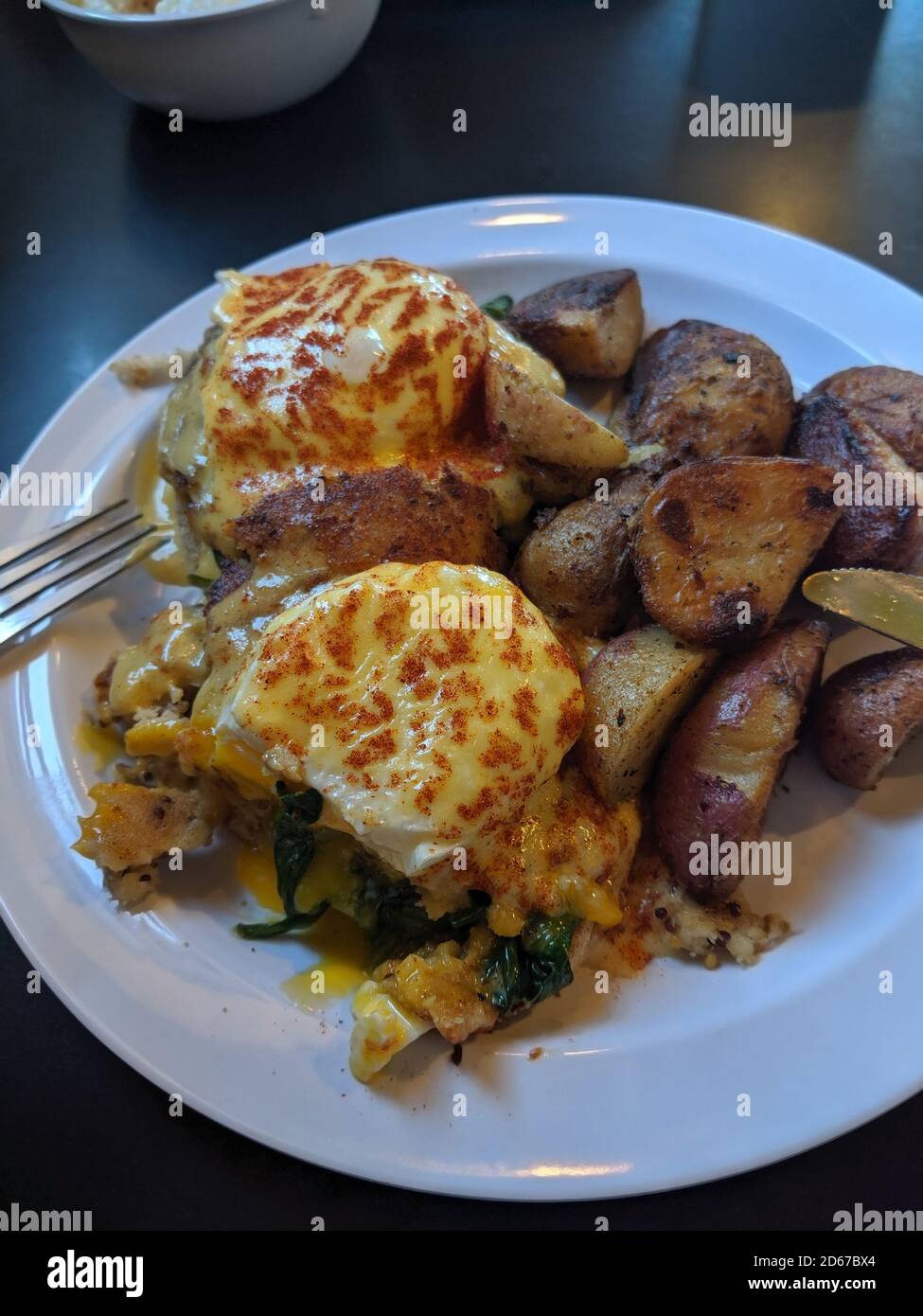 Délicieux repas d'œufs pochés sur un petit pain et rôtis pommes de terre Banque D'Images