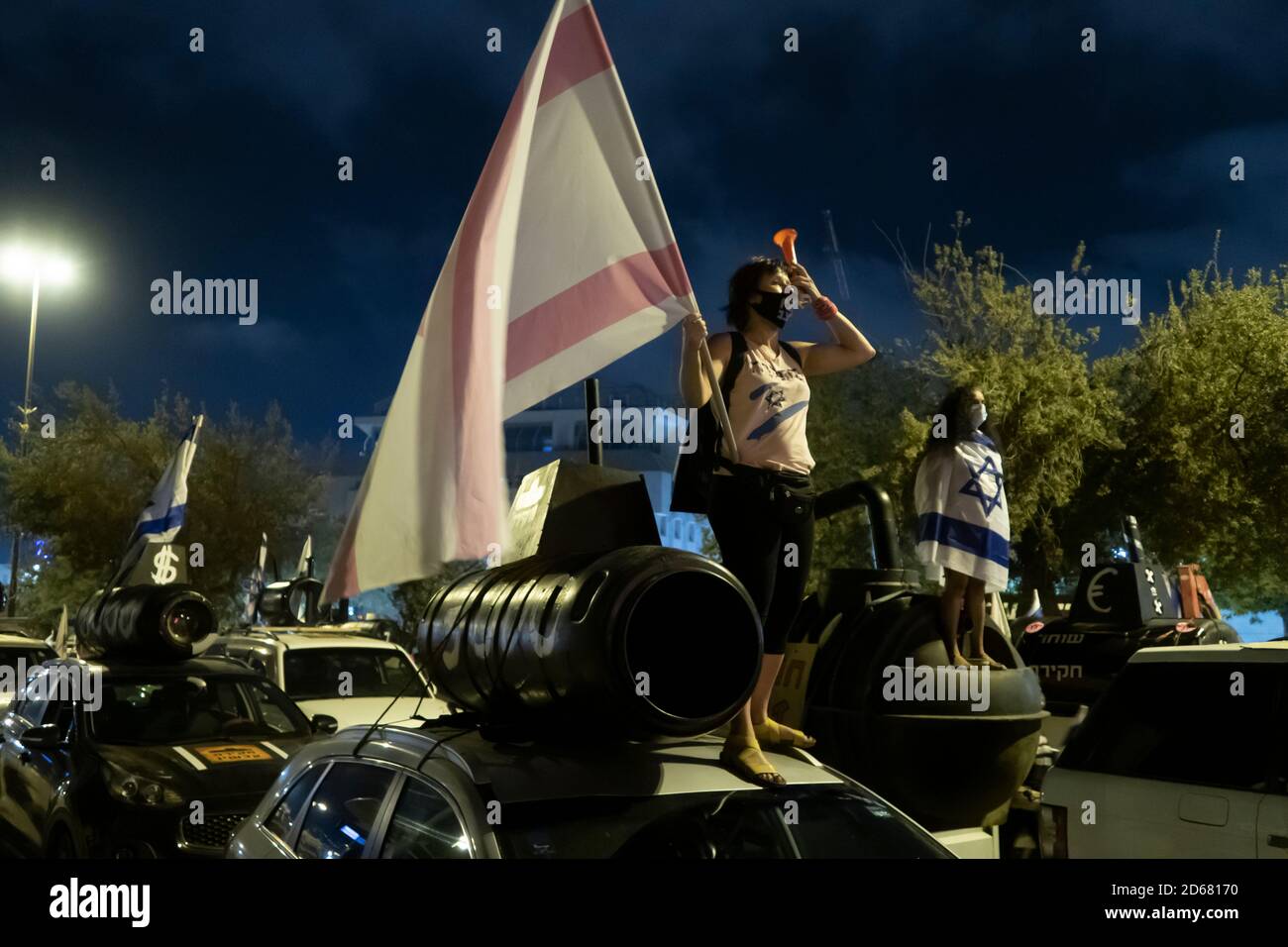 JÉRUSALEM, ISRAËL - 14 OCTOBRE : un manifestant fait passer le drapeau israélien au-dessus d'un sous-marin géant en plastique en référence à ce que l'on appelle l'affaire sous-marine lors d'une protestation contre le PM Netanyahou le 14 octobre 2020 à Jérusalem, en Israël. Des centaines d’Israéliens se sont rassemblés devant la Cour suprême d’Israël pour demander que le Premier ministre Benjamin Netanyahu fasse l’objet d’une enquête dans le cadre d’un scandale autour d’un accord de 2 milliards de dollars sur les sous-marins, qui impliquait la réception de fonds illicites dans le cadre d’un projet de corruption visant à acheter des sous-marins auprès du constructeur de navires allemand ThyssenKrupp. Banque D'Images