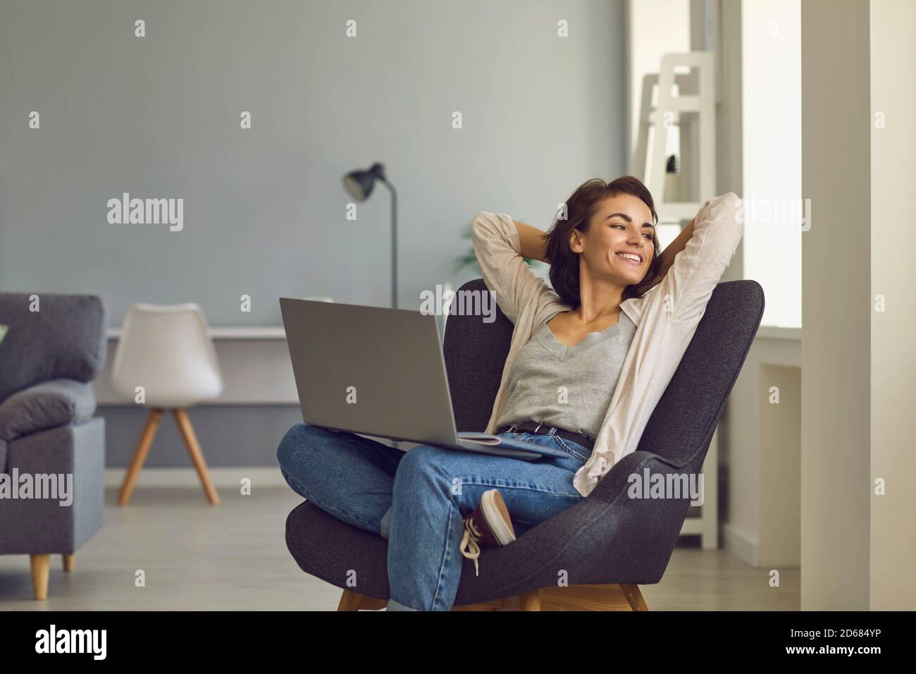 Jeune femme souriante assise avec un ordinateur portable pendant un appel vidéo de accueil Banque D'Images