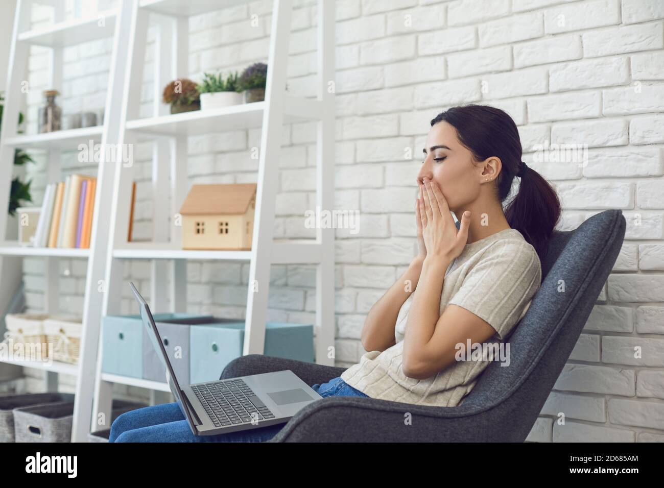 Femme embrassant un interlocuteur virtuel sur l'écran d'un ordinateur portable lors d'une réunion en ligne. Date virtuelle. Banque D'Images