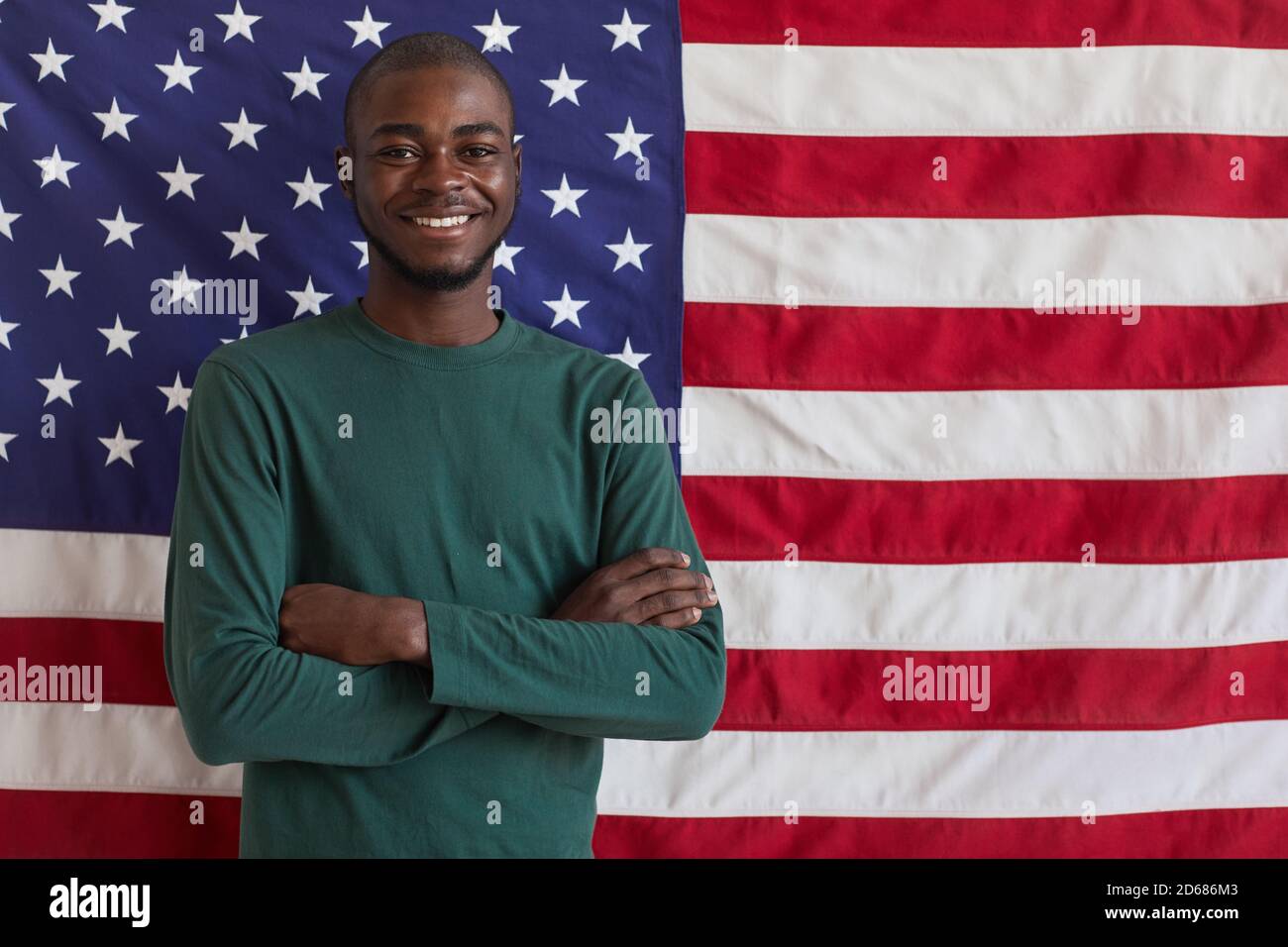 Portrait du jeune afro-américain debout avec les bras croisés et Sourire à la caméra contre le drapeau américain Banque D'Images