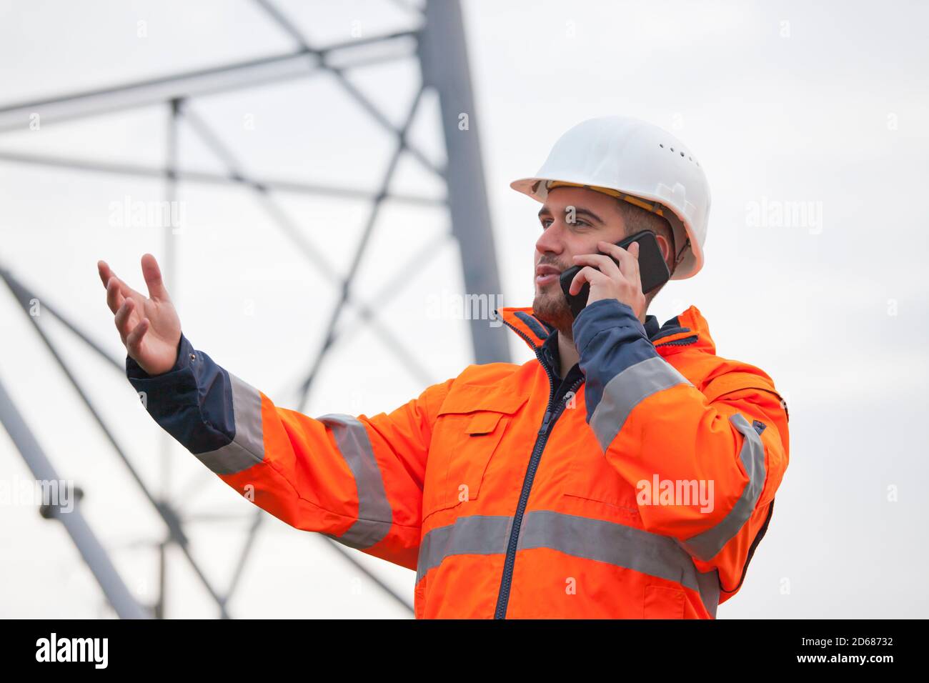 Jeune ingénieur ou contremaître parlant sur un smartphone sur un plate-forme pétrolière ou chantier de construction - attention sélective Banque D'Images