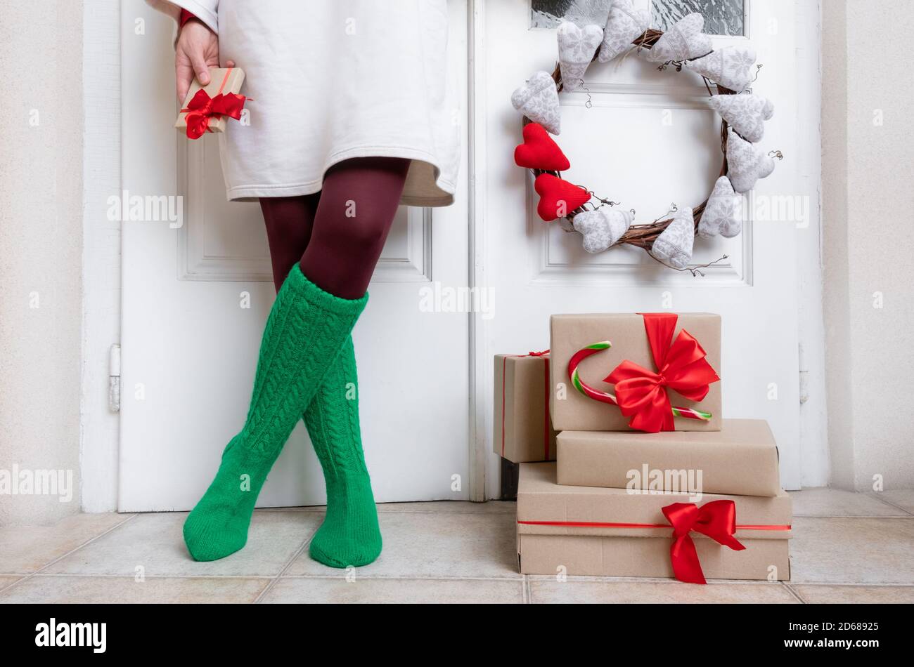 Les pieds de femme en chaussettes vertes se tiennent près de la porte  blanche avec des cadeaux à la veille des fêtes de Noël et du nouvel an  Photo Stock - Alamy