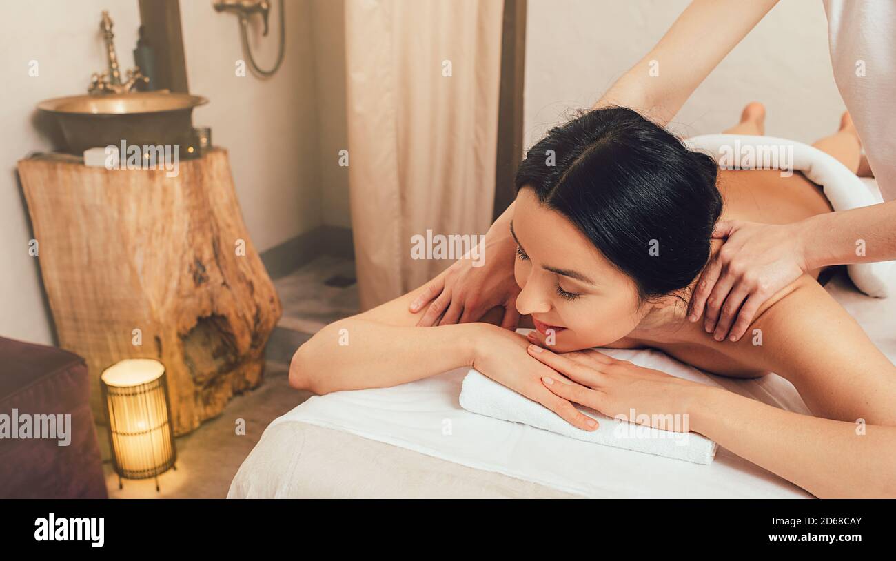 Massage anti-stress. Une belle femme brunette reçoit un massage du dos dans un centre thermal Banque D'Images