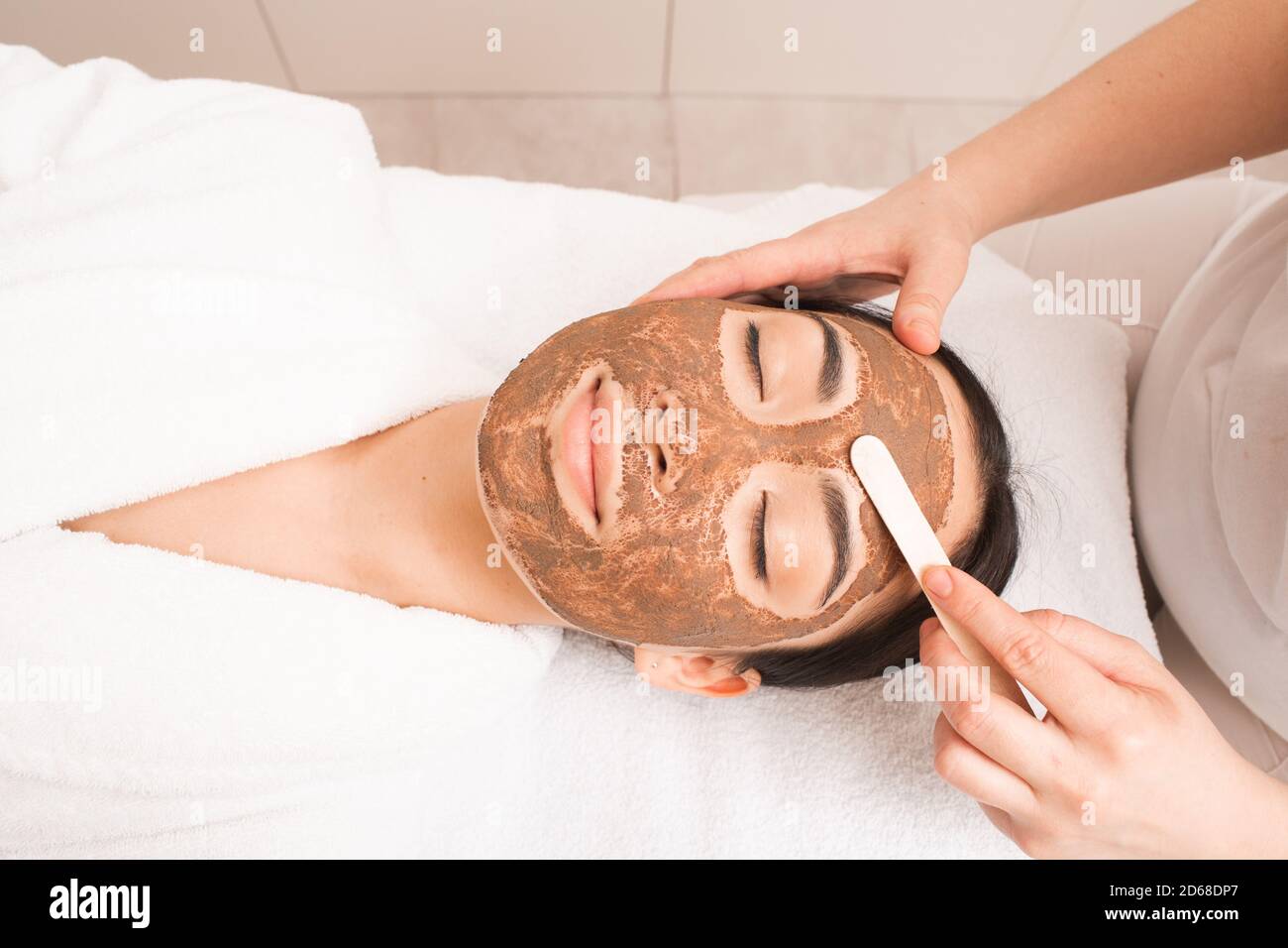 Esthéticienne appliquant un masque de boue sur le visage de la femme. Traitement, nettoyage et adoucissement de la peau. Fait partie d'une série avec masque de boue Banque D'Images