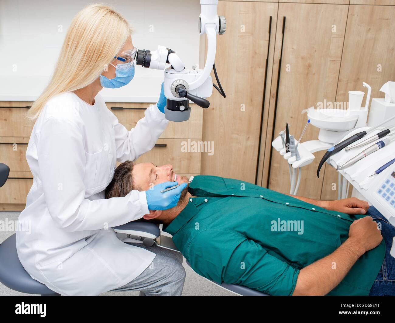 Dentiste examinant un patient mâle à l'aide d'un microscope spécial dans une clinique dentaire moderne Banque D'Images