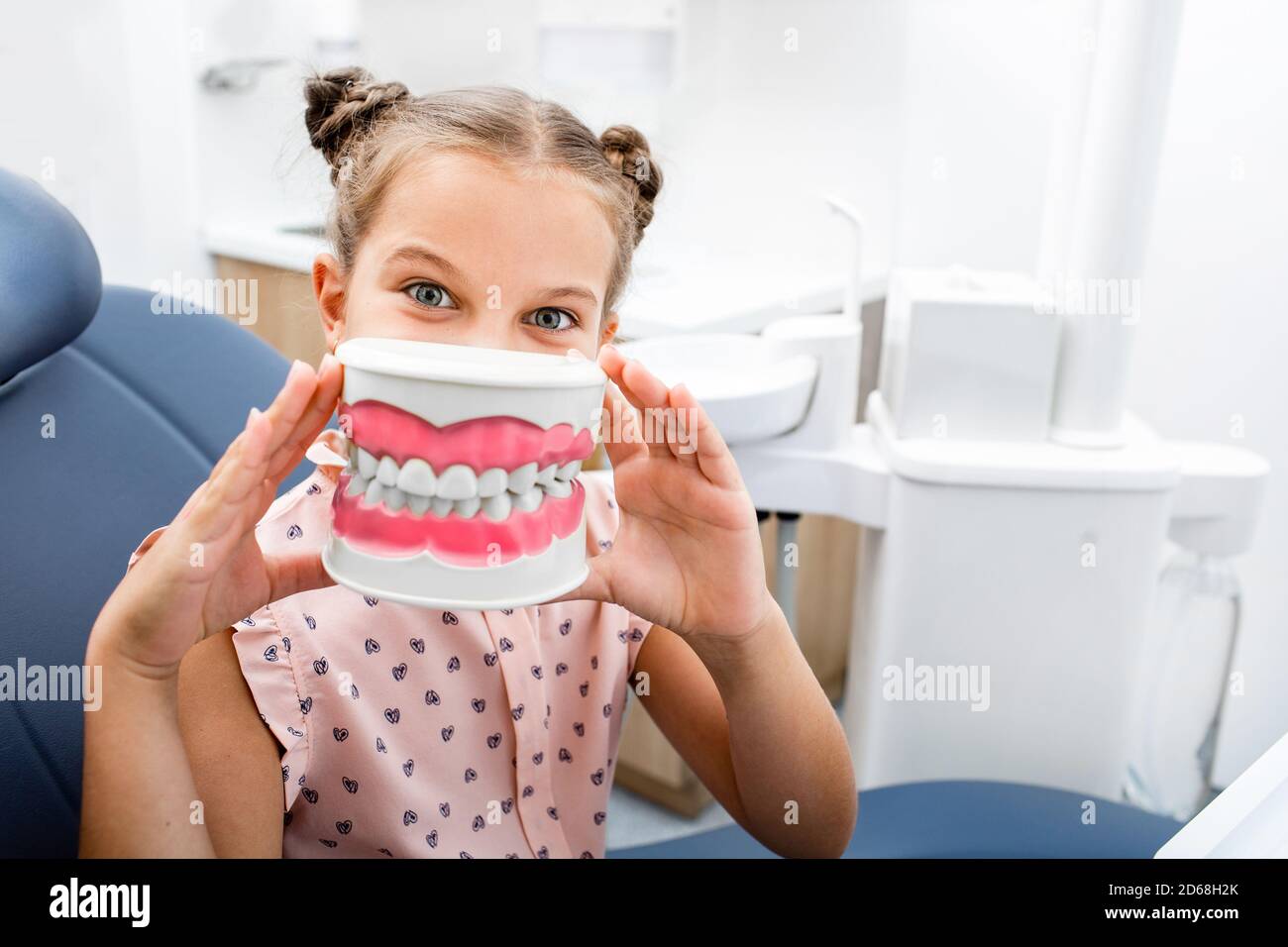 Soins des dents. Petite fille émotive assise dans la chaise du dentiste et souriante Banque D'Images