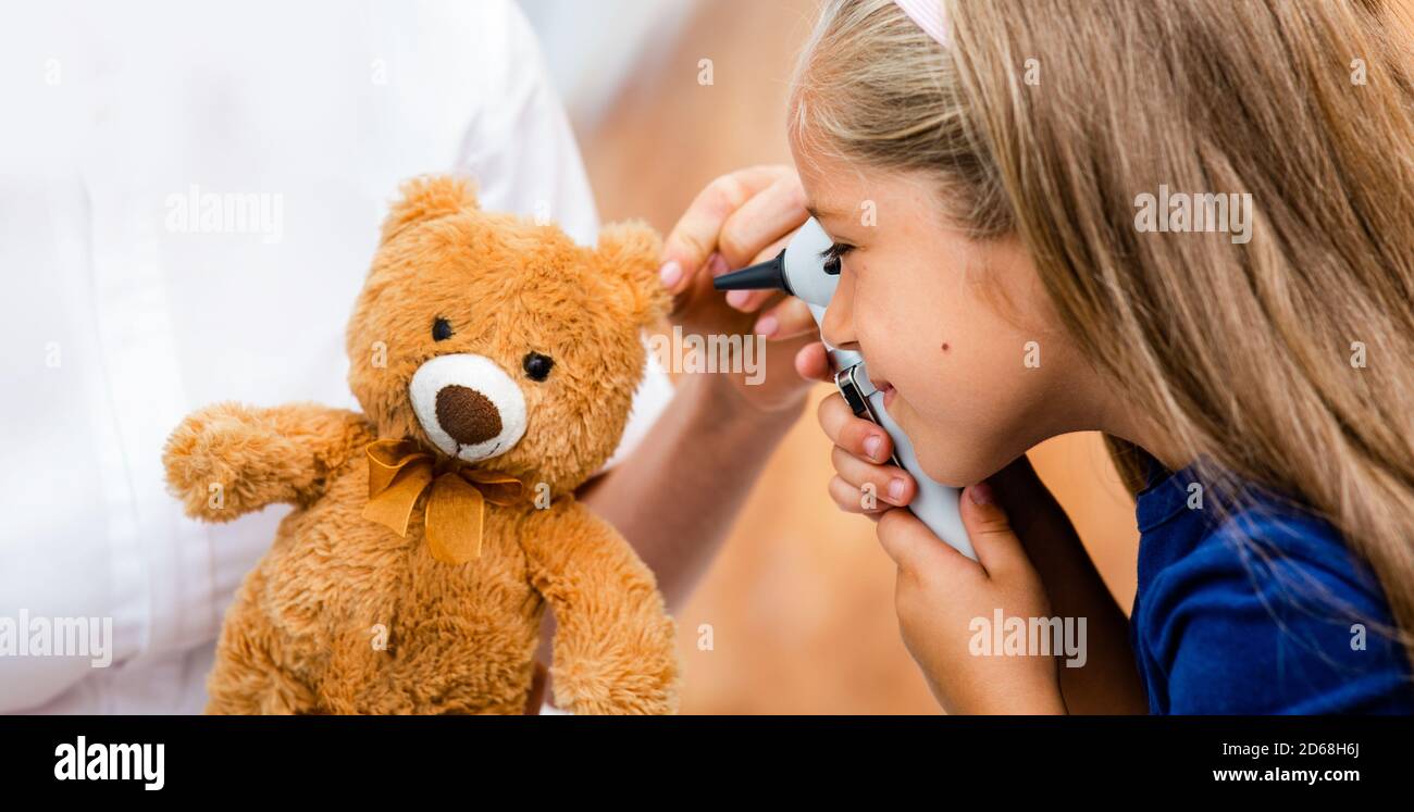 petite fille regardant à travers l'otoscope sur l'oreille du jouet. Contrôle auditif, enfant drôle Banque D'Images