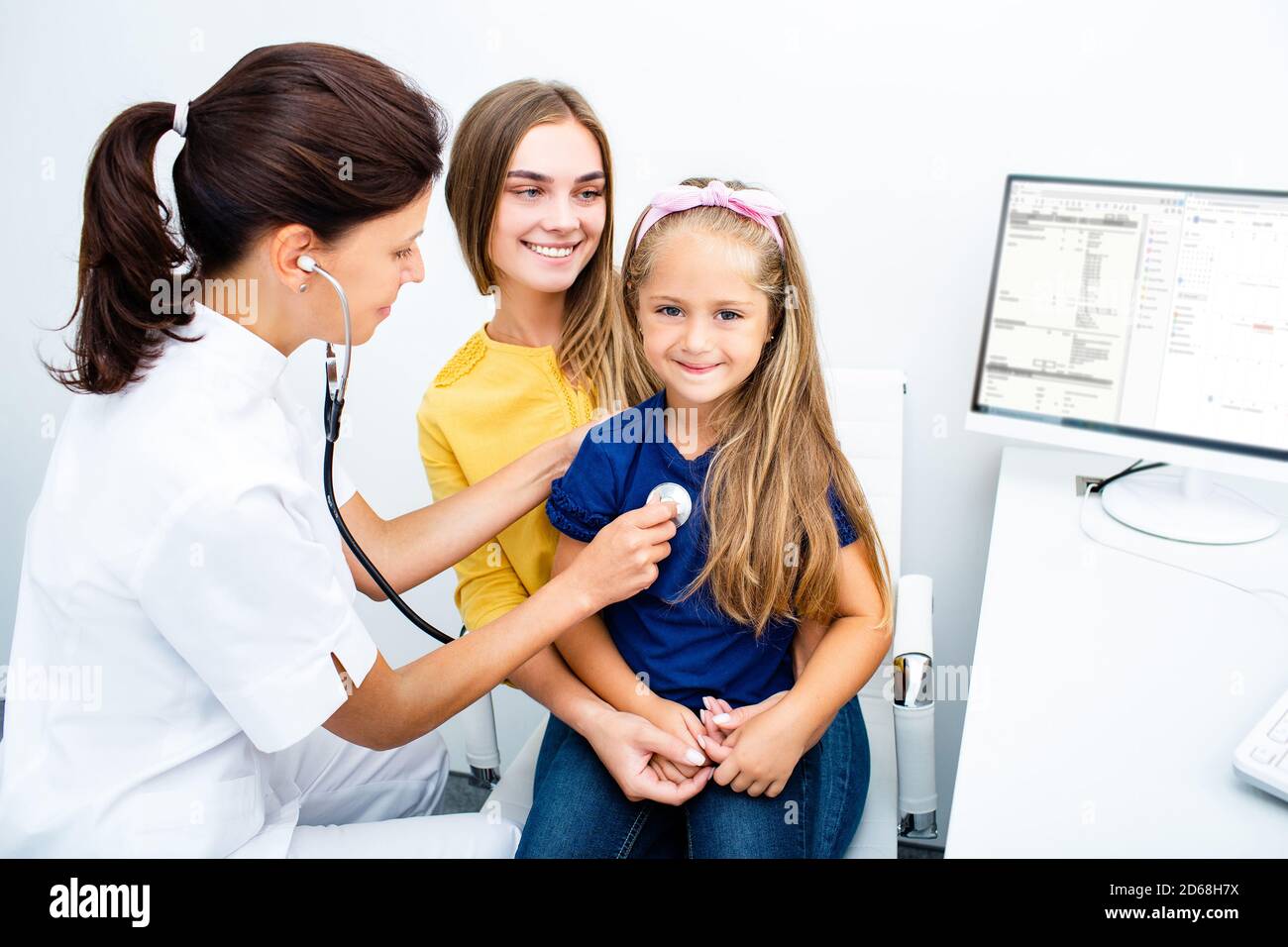Pédiatre tenir un stéthoscope, communiquer avec une jeune fille patient consulter le médecin avec la mère. Vérifier les poumons cardiaques de l'enfant Banque D'Images