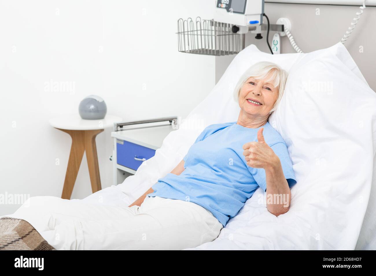 Femme âgée montrant les pouces vers le haut alors qu'elle était allongée dans un lit d'hôpital. la santé du patient est bonne Banque D'Images