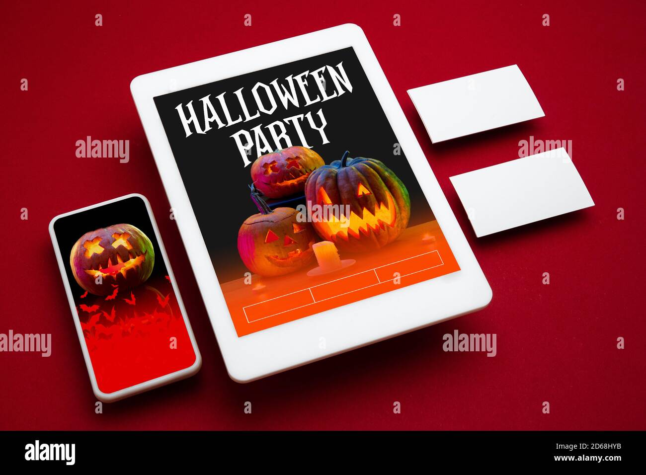 Citrouille effrayante sur l'écran de l'appareil et sur fond rouge. Jack-o-lanternes avec bougies. Halloween, vendredi noir, cyber lundi, ventes, fête, concept d'automne. Tablette et carte d'argent. Cartes d'invitation, promotion. Banque D'Images