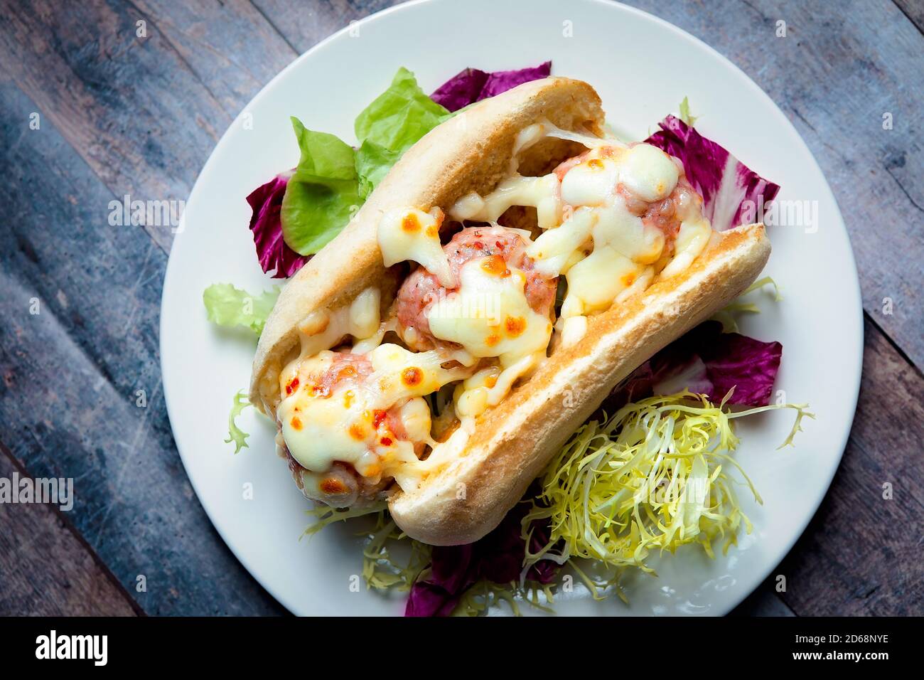 Photo de haut en bas d'un sandwich meatball servi dans un chaud petit pain pour chien avec fromage fondu et salade mixte Banque D'Images