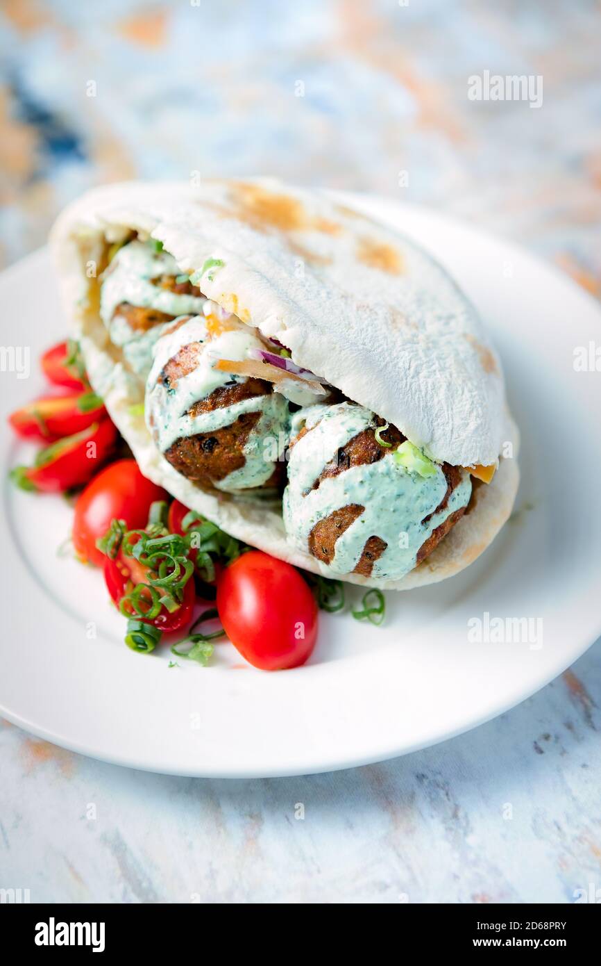 Sandwich pitta pain meatball servi avec une sauce au yaourt et de la cerise tomates sur le côté Banque D'Images