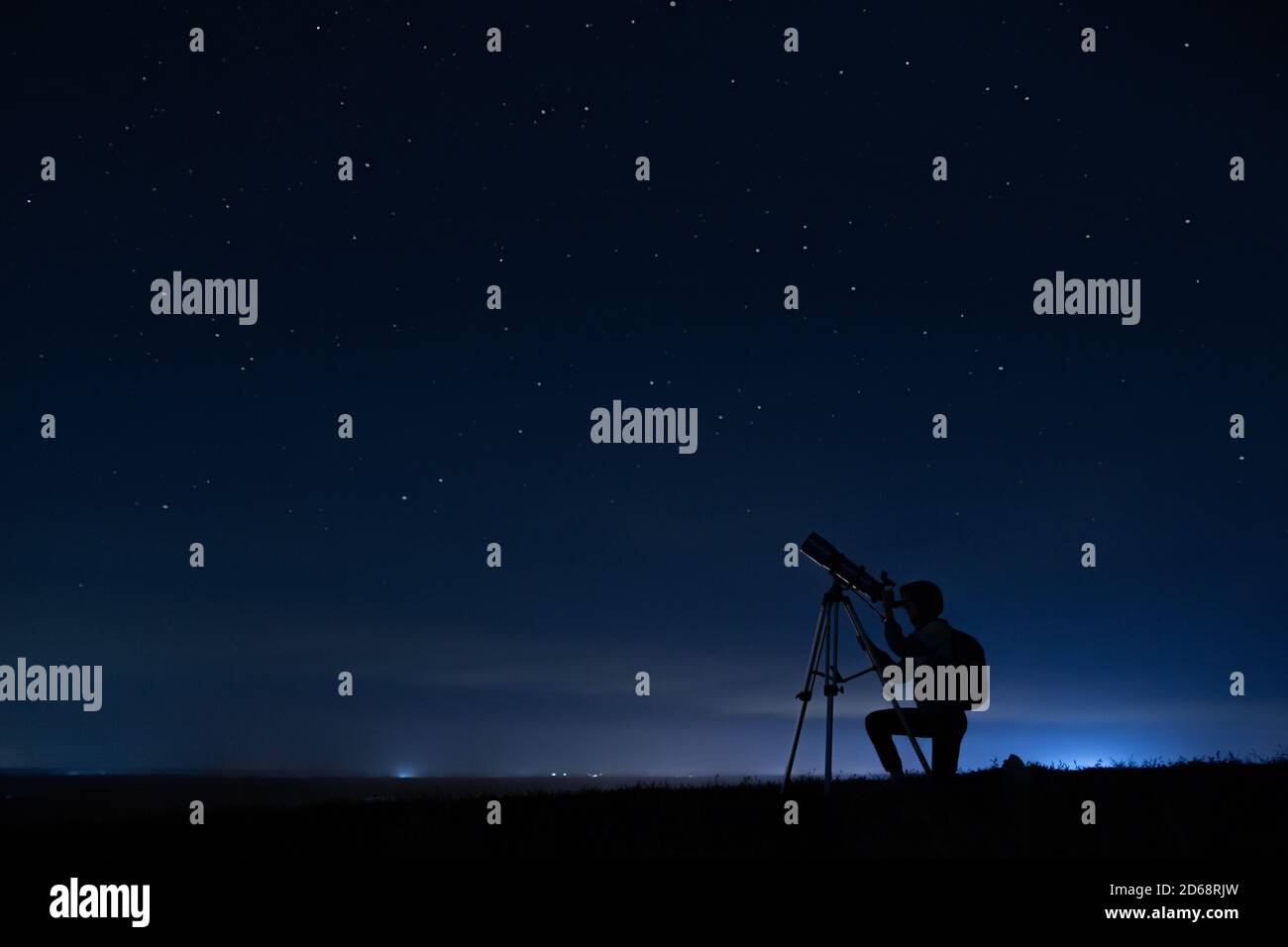 Silhouette humaine et télescope, une femme regarde à travers un télescope au ciel étoilé. Ciel nocturne, étoiles, exposition longue, astronomie Banque D'Images