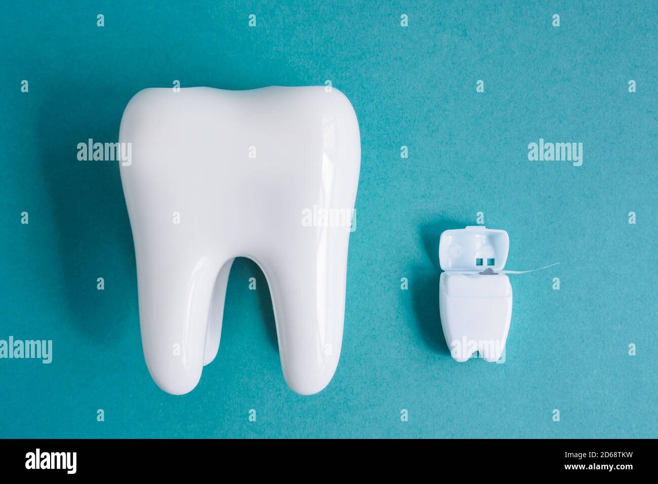 Vue de dessus du modèle de dents blanches saines et de la soie dentaire dans un récipient blanc sur fond bleu Banque D'Images