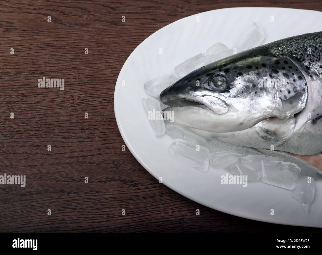 Poisson de saumon sur glace sur un plateau blanc. Table en bois. Banque D'Images