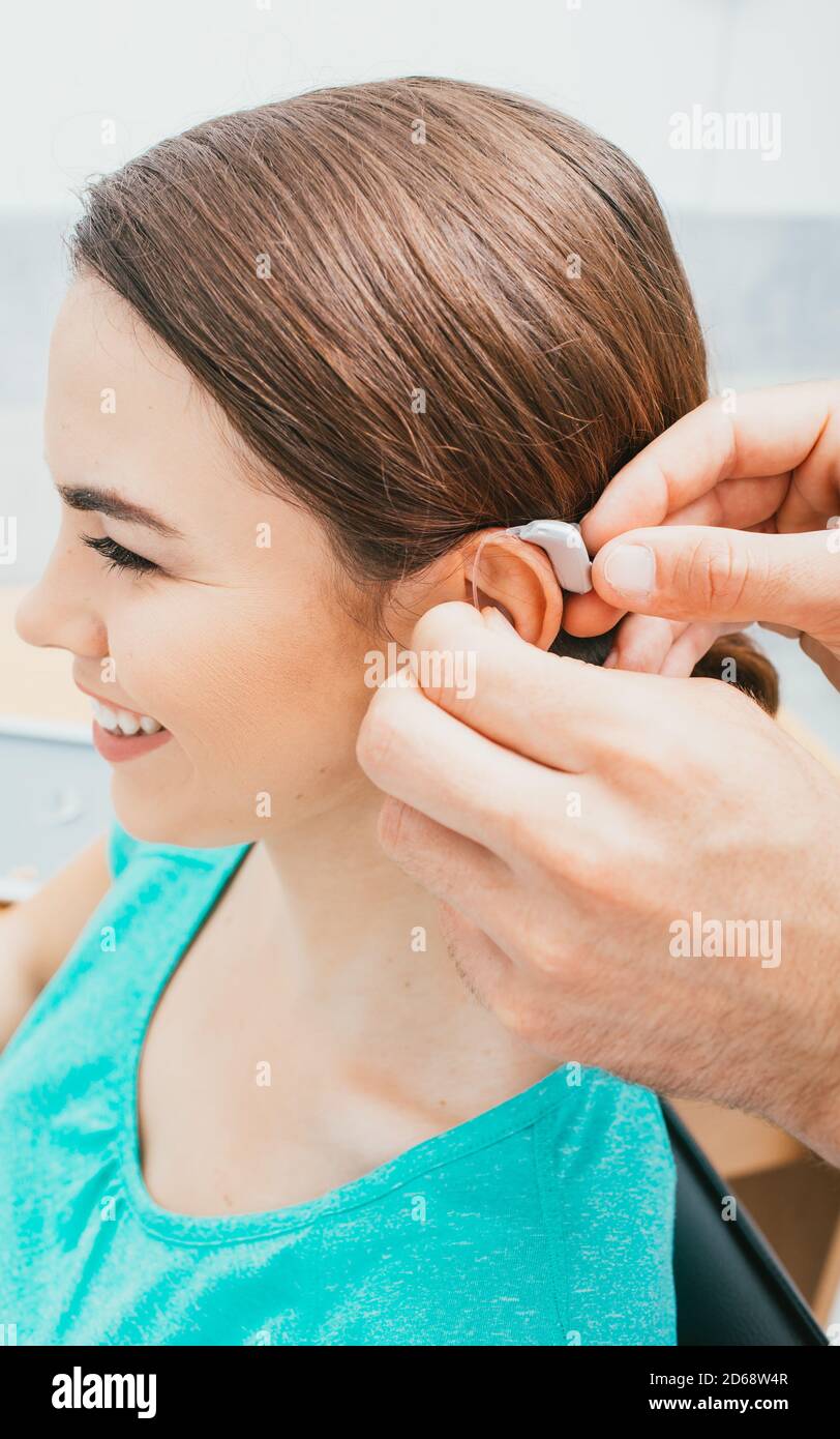 Audiologiste insertion de l'aide auditive sur l'oreille femelle, gros plan . Traitement de la surdité, solution auditive Banque D'Images