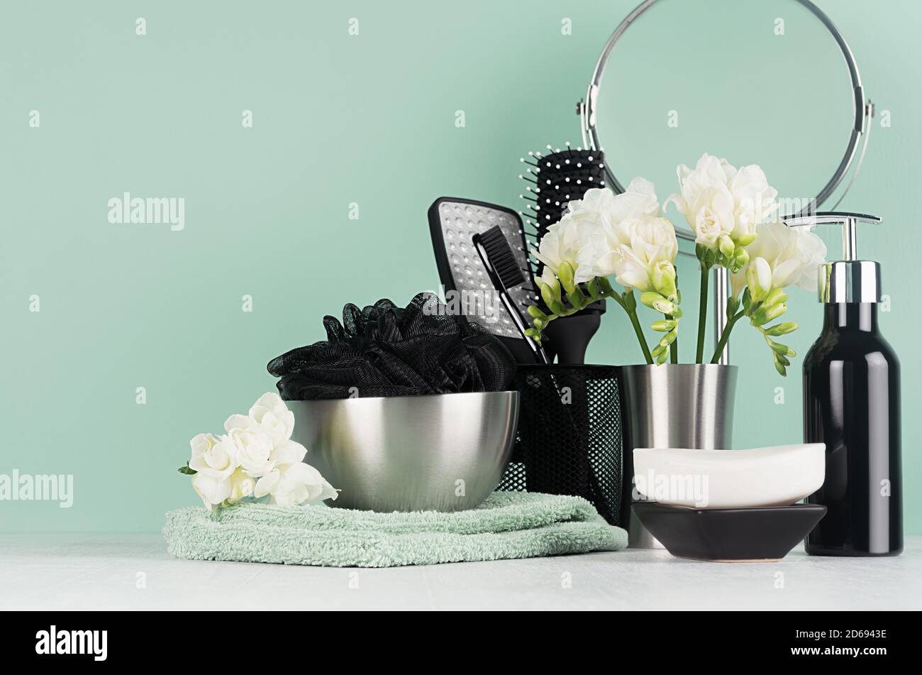 Produits de toilette noirs élégants - distributeur, brosse à dents, brosse, éponge de bain, savon, miroir rond, fleurs blanches, serviette sur bois blanc et couleur menthe aqua W Banque D'Images