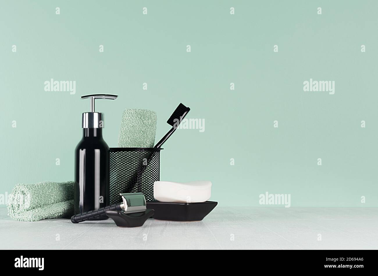 Intérieur frais de salle de bains à la menthe verte menthe couleur - rasoir noir, brosse à dents, savon, serviette, distributeur sur table en bois blanc. Banque D'Images