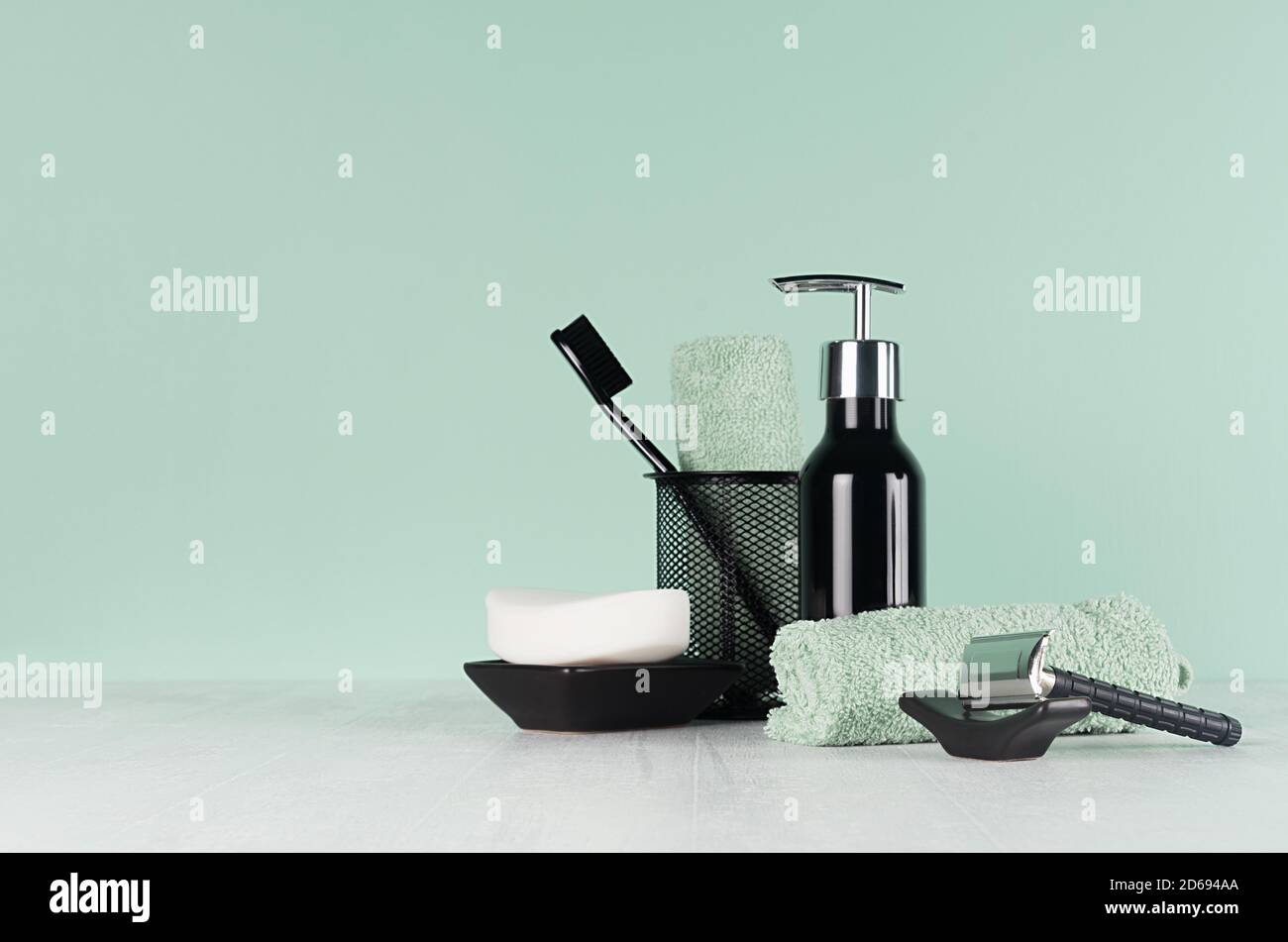 Élégante coiffeuse d'hommes dans la tendance vert menthe menthe couleur - rasoir noir, brosse à dents, savon, serviette, distributeur sur table en bois blanc clair. Banque D'Images