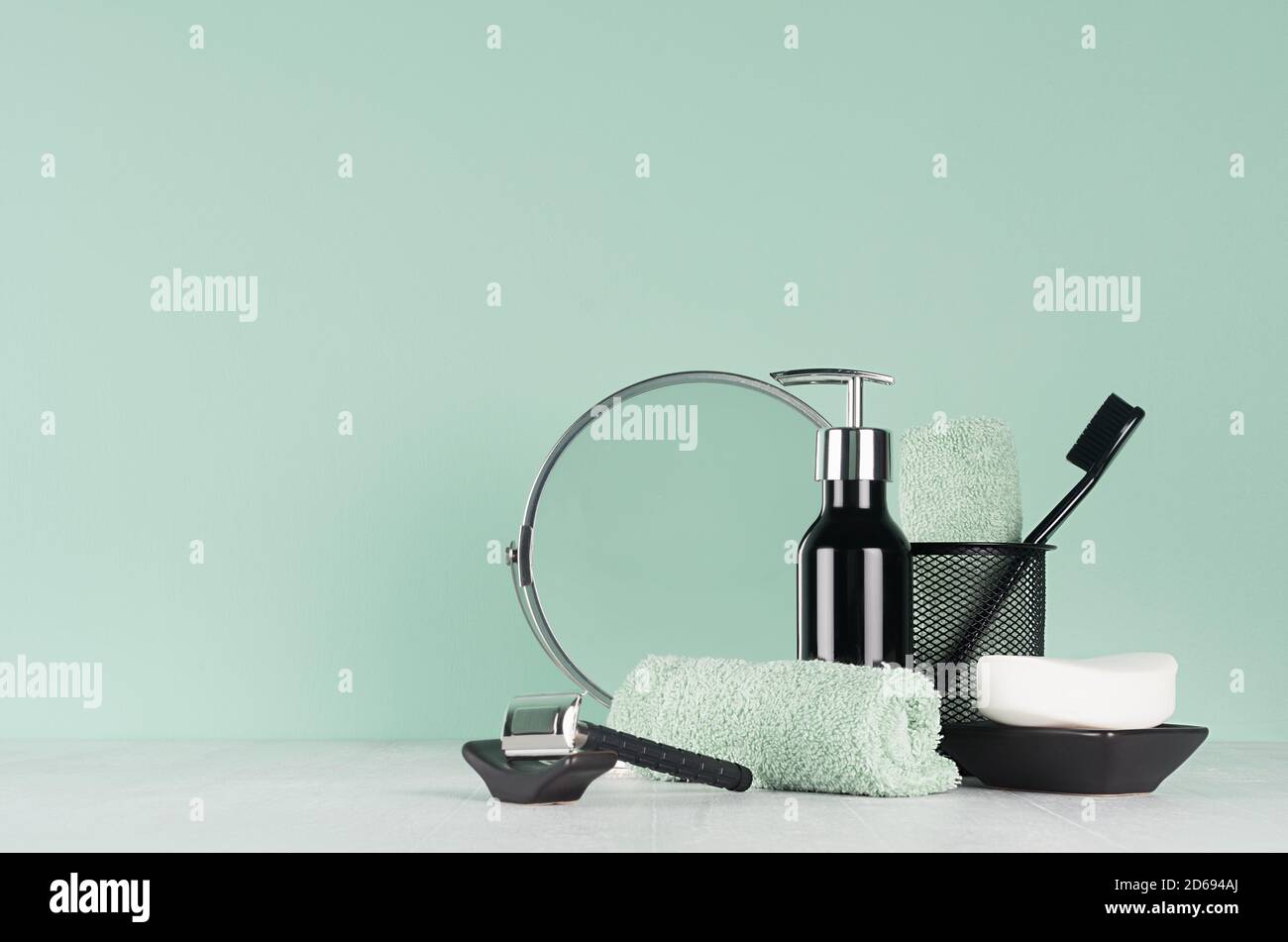 Produits de toilette noirs élégants pour le rasage : rasoir noir, savon, miroir rond, serviette, brosse à dents sur panneau en bois blanc et mur couleur menthe aqua, espace de copie, encre Banque D'Images