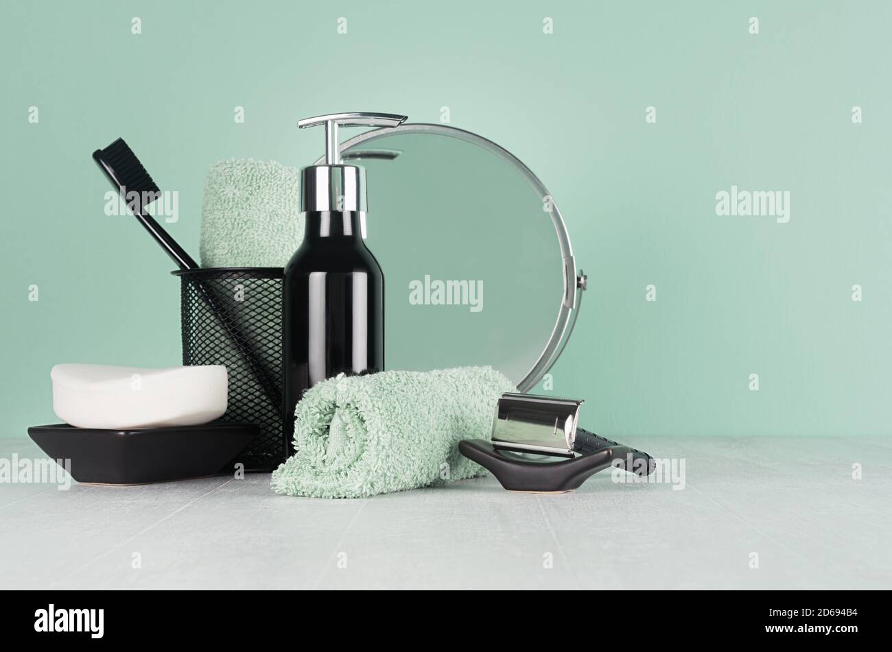 Élégante coiffeuse d'hommes dans la tendance vert menthe menthe couleur - rasoir noir, brosse à dents, miroir, savon, serviette, distributeur sur table en bois blanc clair. Banque D'Images