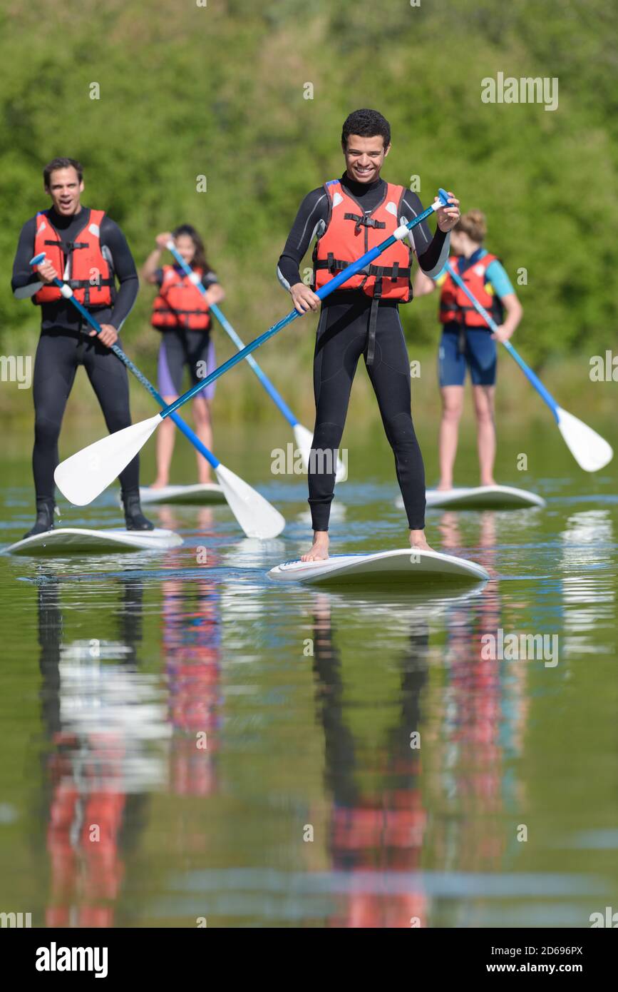 les gens se tiennent debout sur des planches de paddle sur un lac Banque D'Images