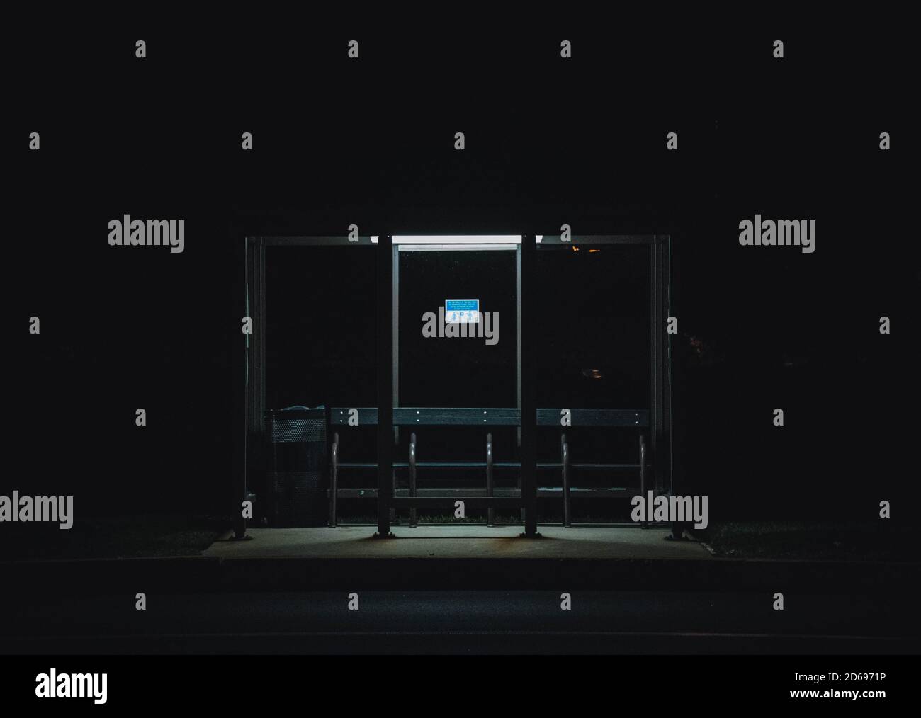 Une seule lumière dans l'obscurité illumine un arrêt de bus. Banque D'Images