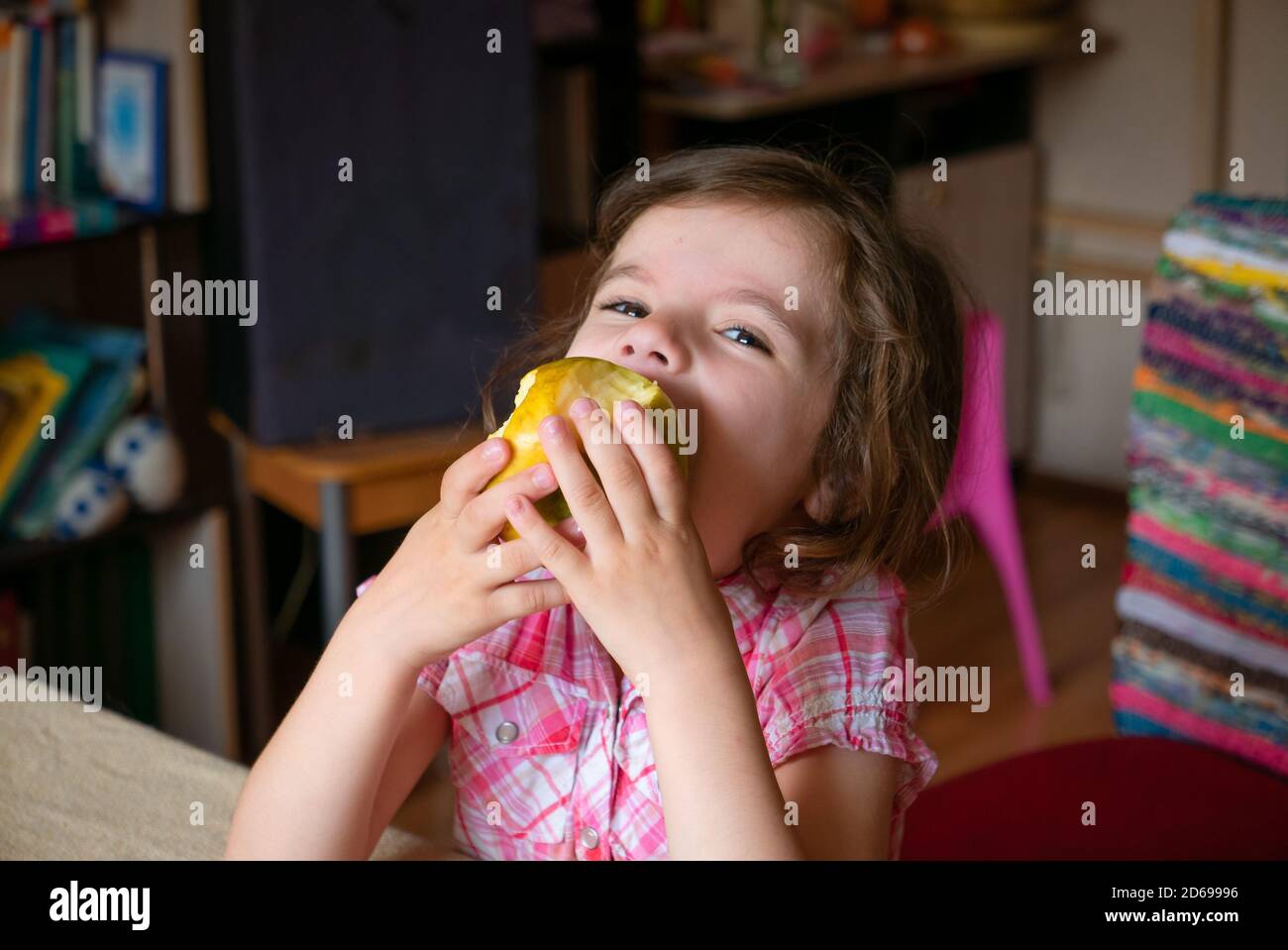 Drôle adorable petite fille mange une pomme. Banque D'Images