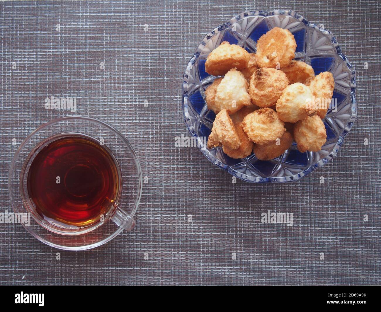 Sur la table, recouverte d'un tissu brun, se trouve une tasse de thé et un bol de biscuits. Encore-vie. Banque D'Images