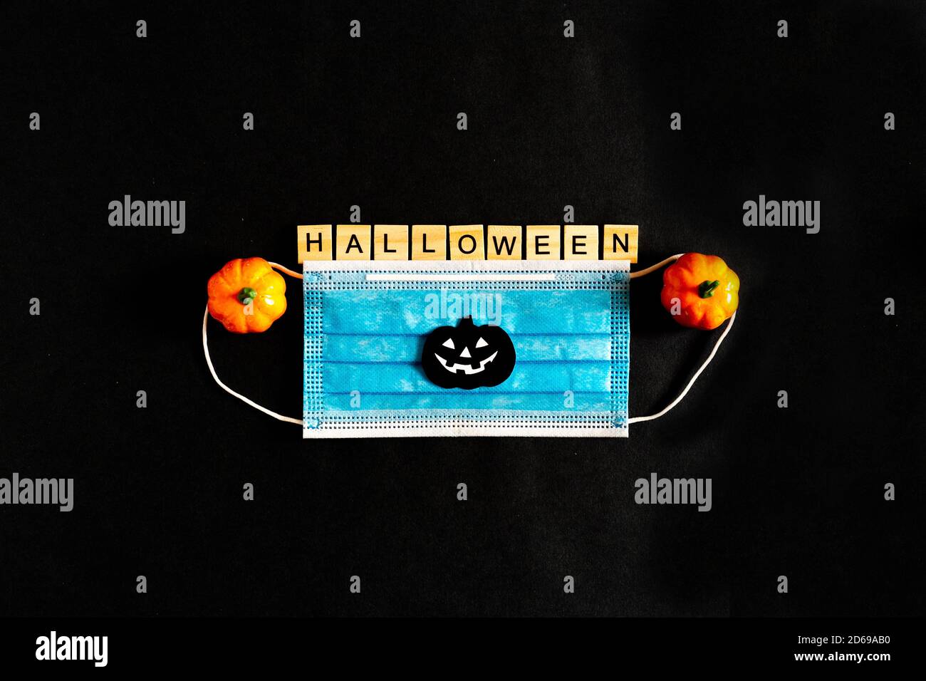 Citrouilles d'Halloween, masque médical protecteur et feuilles d'érable jaune sur fond noir, chauves-souris en papier noir. L'inscription HALLOWEEN le Banque D'Images