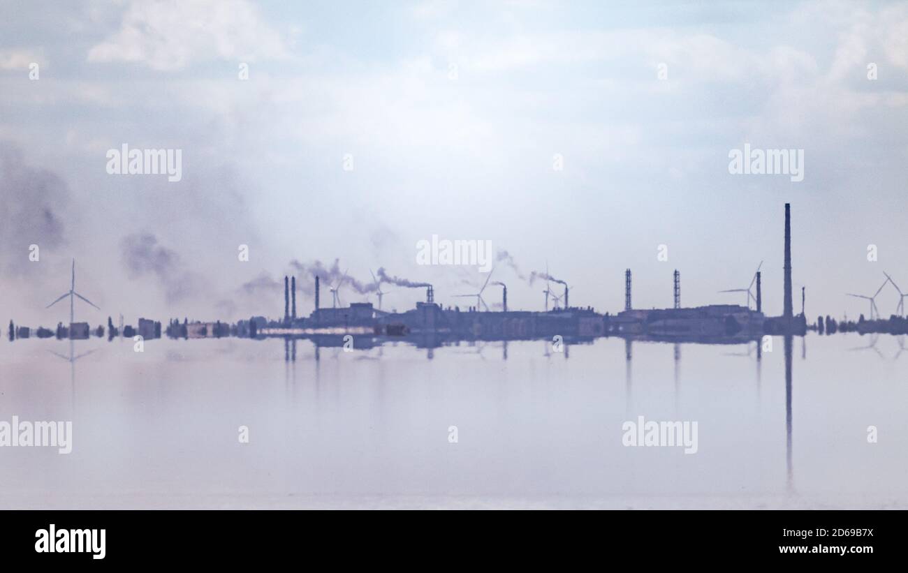 Lac reflet de l'eau bleu paysage nuageux avec tuyaux d'usine à une distance. Fumée industrielle polluant l'air. Banque D'Images
