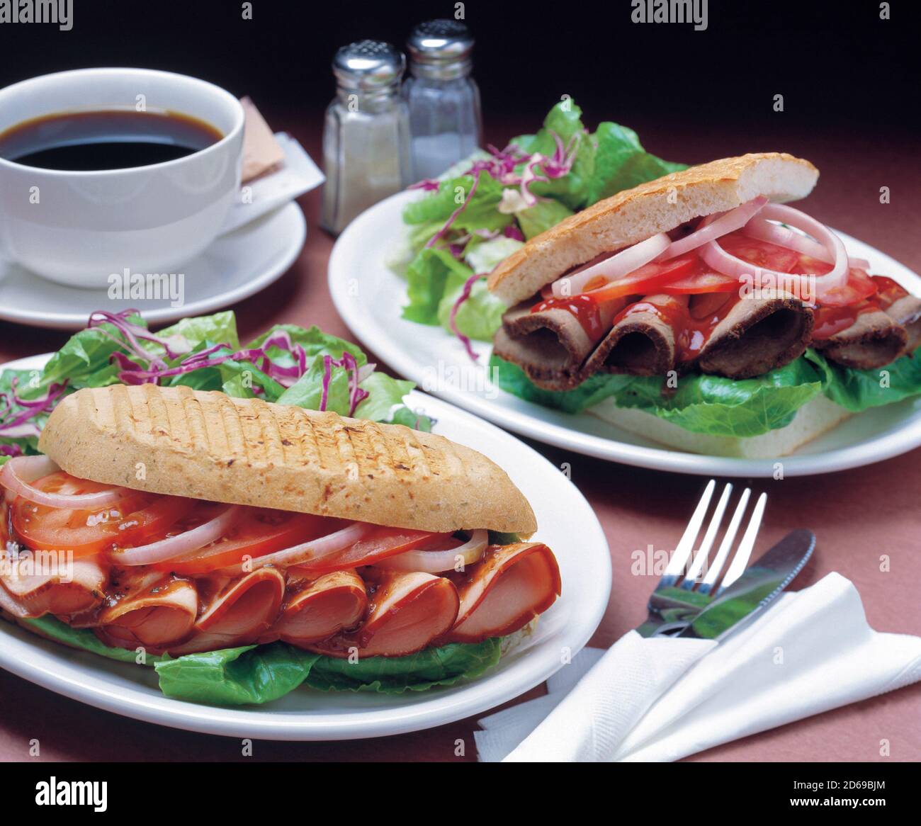 Deux sandwichs avec légumes frais, jambon, tomate et oignon dans du pain ciabatta servi avec une tasse de café Banque D'Images