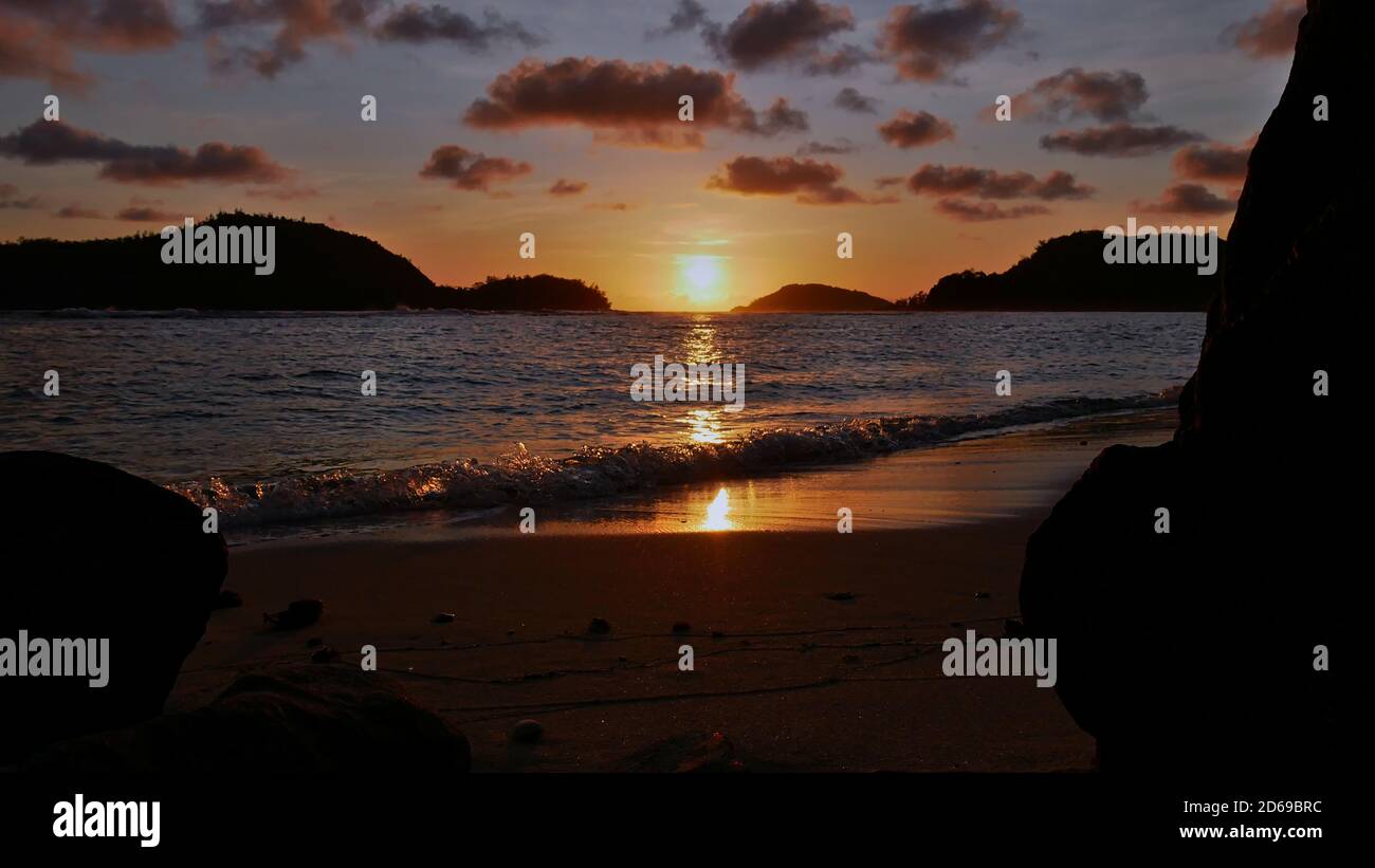 Coucher de soleil majestueux sur la plage tropicale près de Port Launay dans le nord de Mahé, Seychelles avec soleil de couleur orange entre les silhouettes de deux îles. Banque D'Images