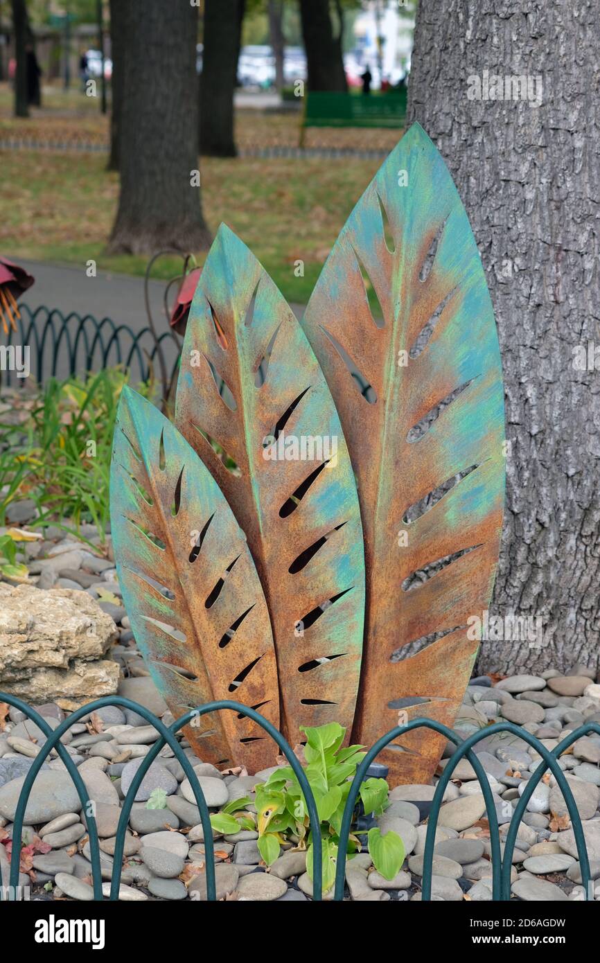 Feuilles de tôle pour l'aménagement paysager. Éléments décoratifs métalliques pour la décoration de parterres de fleurs dans les parcs. Trois feuilles décoratives vertes sont disposées ve Banque D'Images