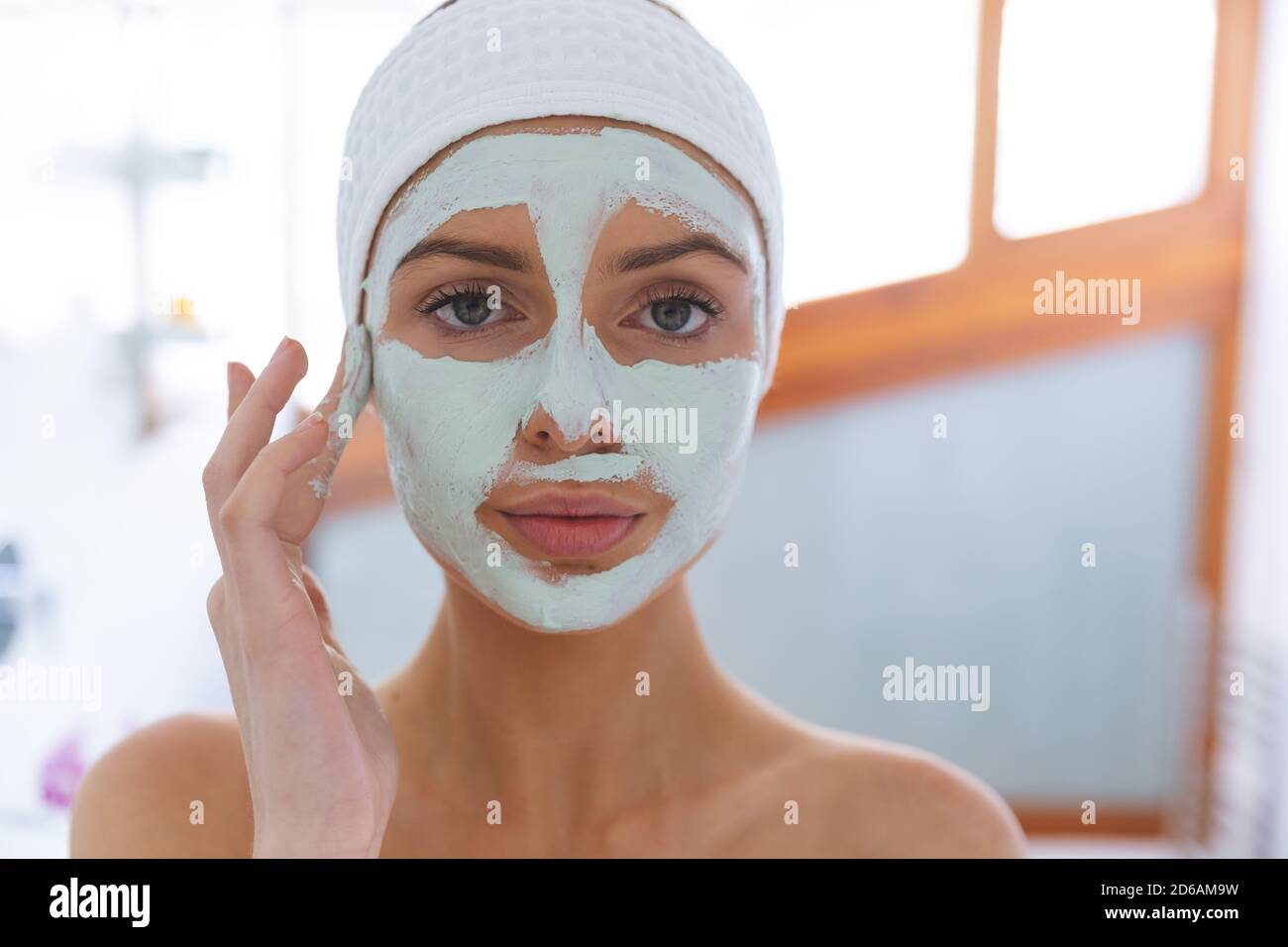 Portrait d'une femme appliquant un paquet de visage dans la salle de bains Banque D'Images