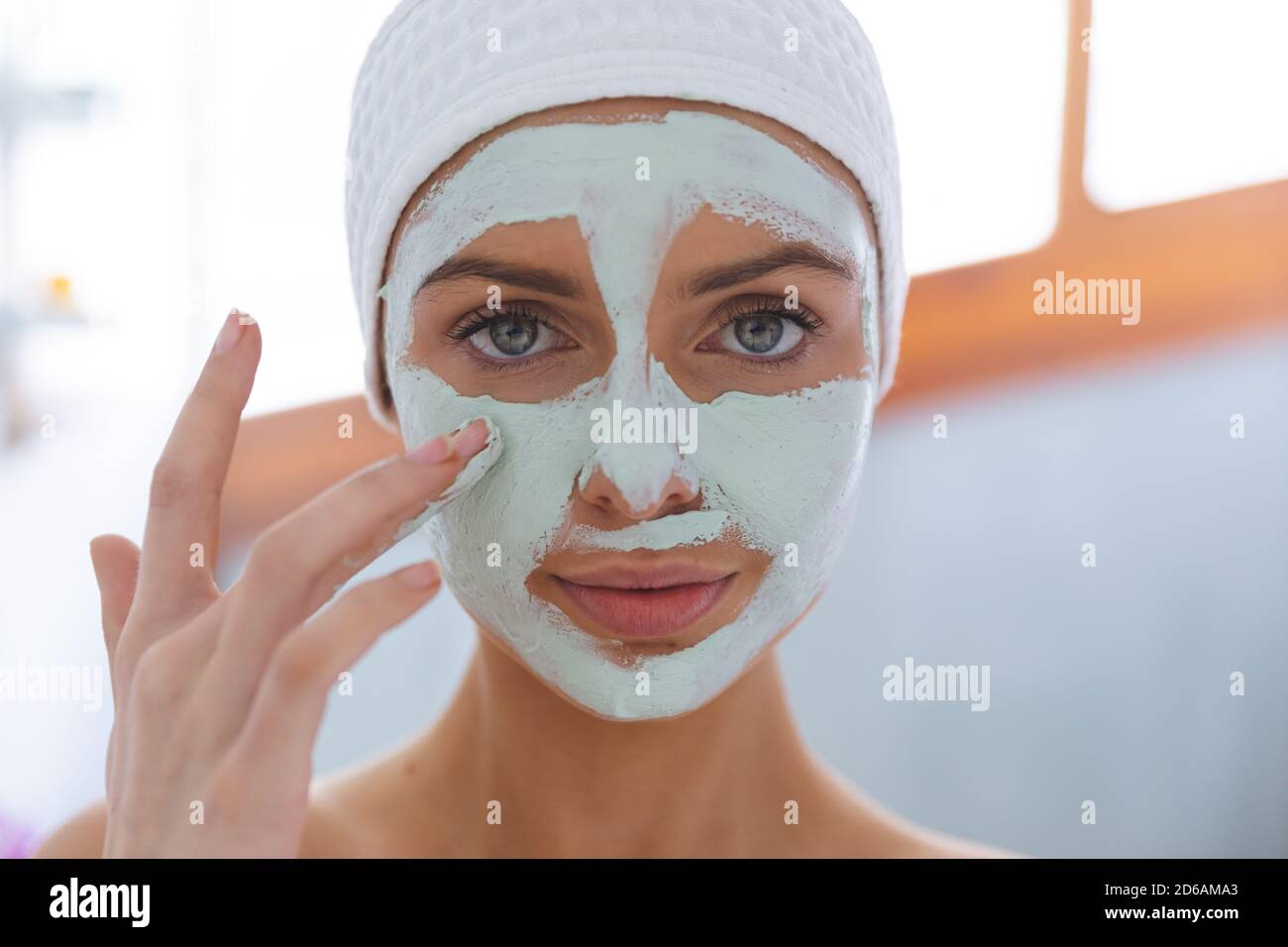 Portrait d'une femme appliquant un paquet de visage dans la salle de bains Banque D'Images