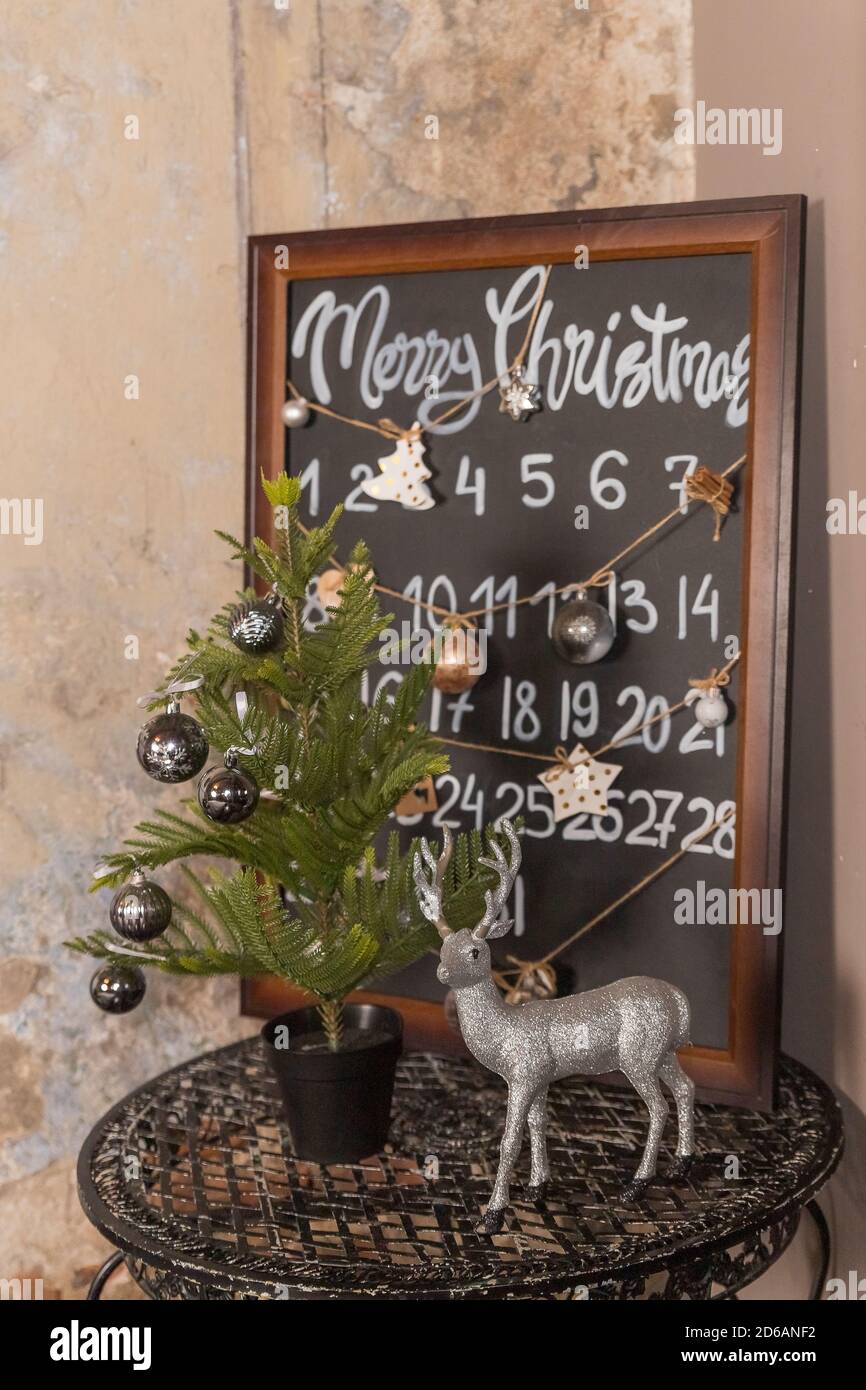 Compte à rebours jusqu'au calendrier de l'Avent de Noël. Décoration de Noël avec petit sapin, décoration, boules, bougies, renne et tableau noir sur fond gris Banque D'Images