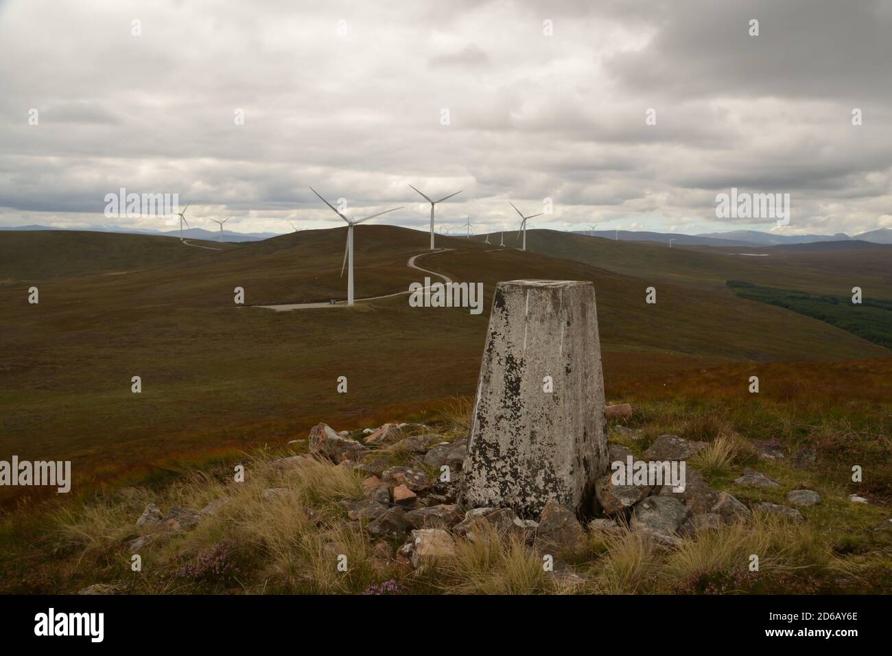 L'Ordnance Survey trig point sur le sommet de la colline Meall a' Gruididh avec un parc à vent derrière, près de Lairg, Scottish Highlands, Royaume-Uni. Banque D'Images