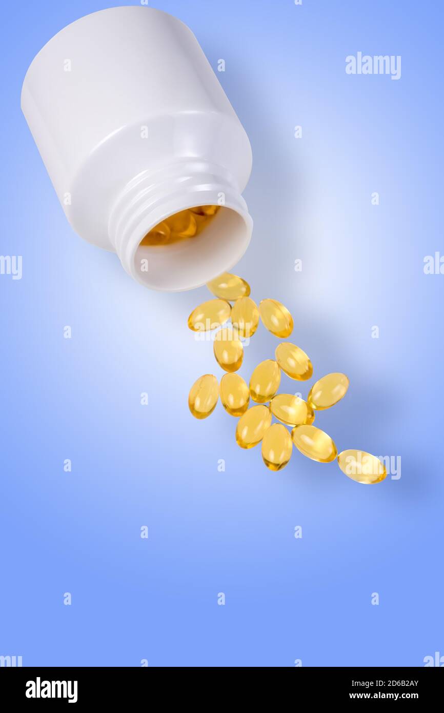 Capsules de vitamine D dispersées sur fond bleu. Additif alimentaire Banque D'Images