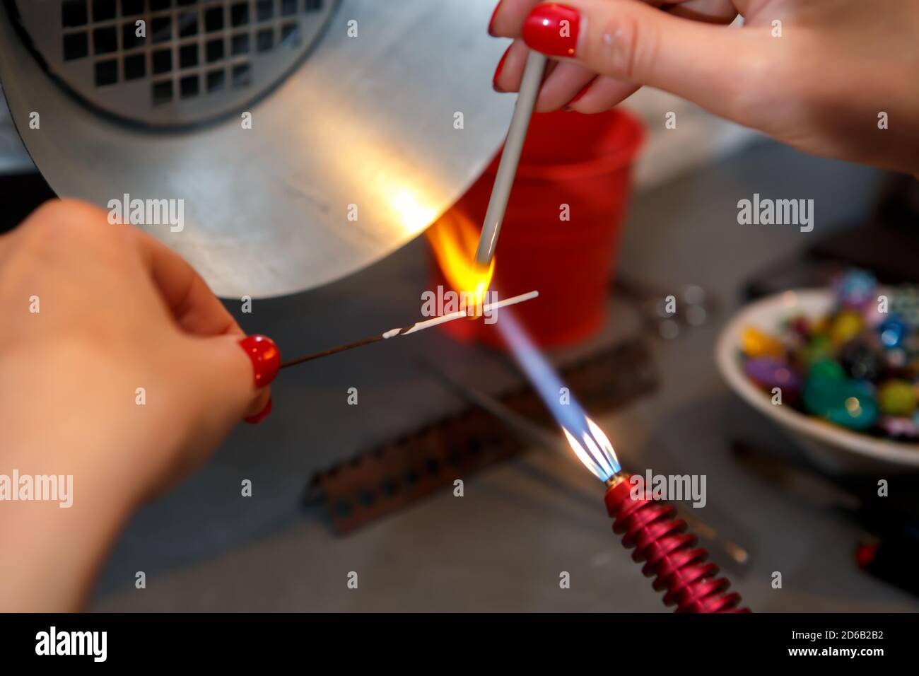 L'artiste chauffe le verre avec un brûleur à gaz. Le processus de fabrication de bijoux en verre. Les mains du maître se rapprochent Banque D'Images