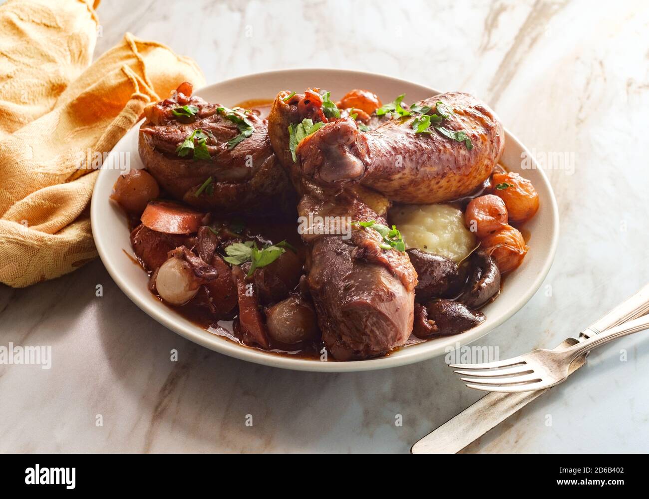 Cuisine française Coq au vin ragoût avec des champignons crimini oignons perlés et carottes dans une sauce au brandy au vin rouge servie sur une purée de pommes de terre Banque D'Images