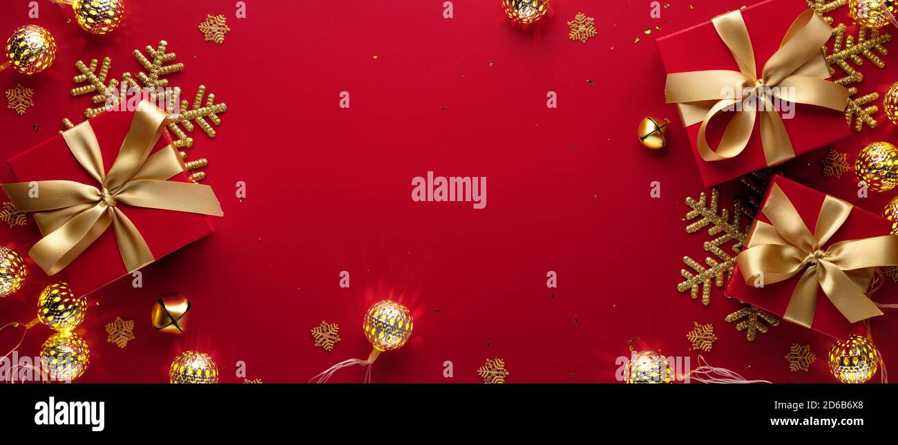 Boules de Noël dorées, flocons de neige et boîte cadeau sur fond rouge Banque D'Images