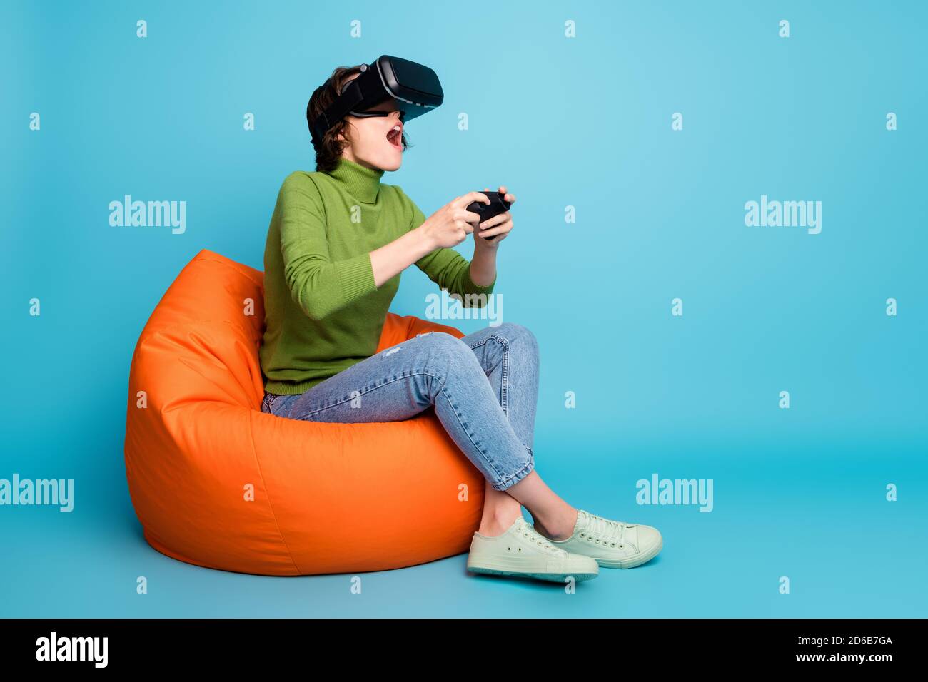 Pleine taille profil photo de côté de fille émerveillement jouer vidéo jeu ont des lunettes virtuelles regarder réalité vr porter pull vert jean denim bleu isolé Banque D'Images