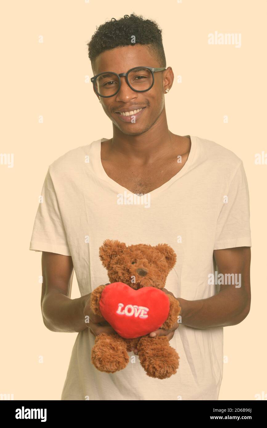 Jeune homme africain heureux tenant l'ours en peluche avec amour et Enseigne en forme de coeur prête pour la Saint-Valentin Banque D'Images