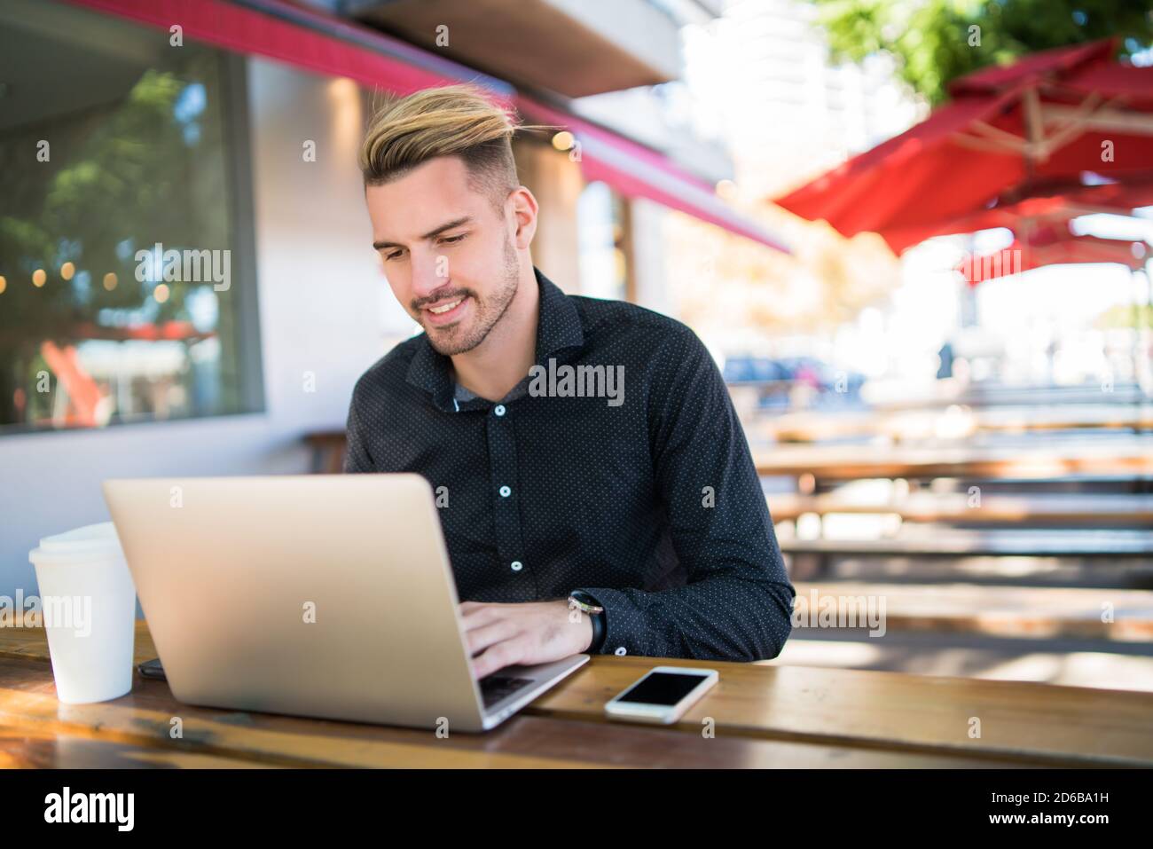 Portrait d'un jeune homme d'affaires travaillant sur son ordinateur portable assis dans un café. Concept de technologie et d'entreprise. Banque D'Images
